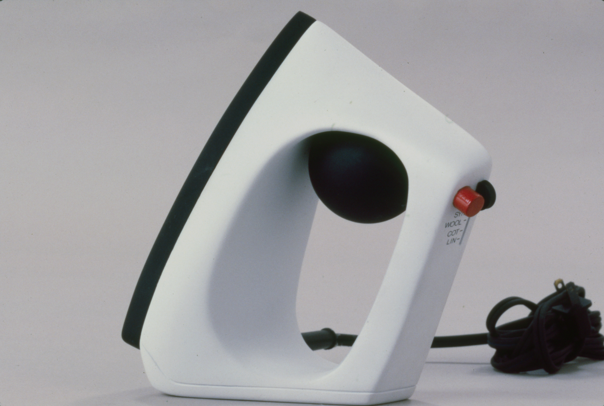 a small white clothes iron with a handle and a red button