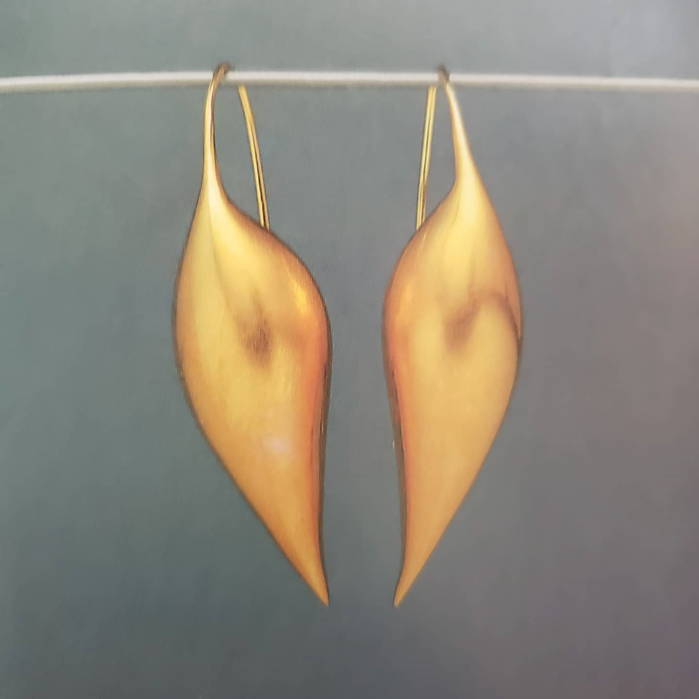 a pair of gold earrings shaped like pointy seed pods