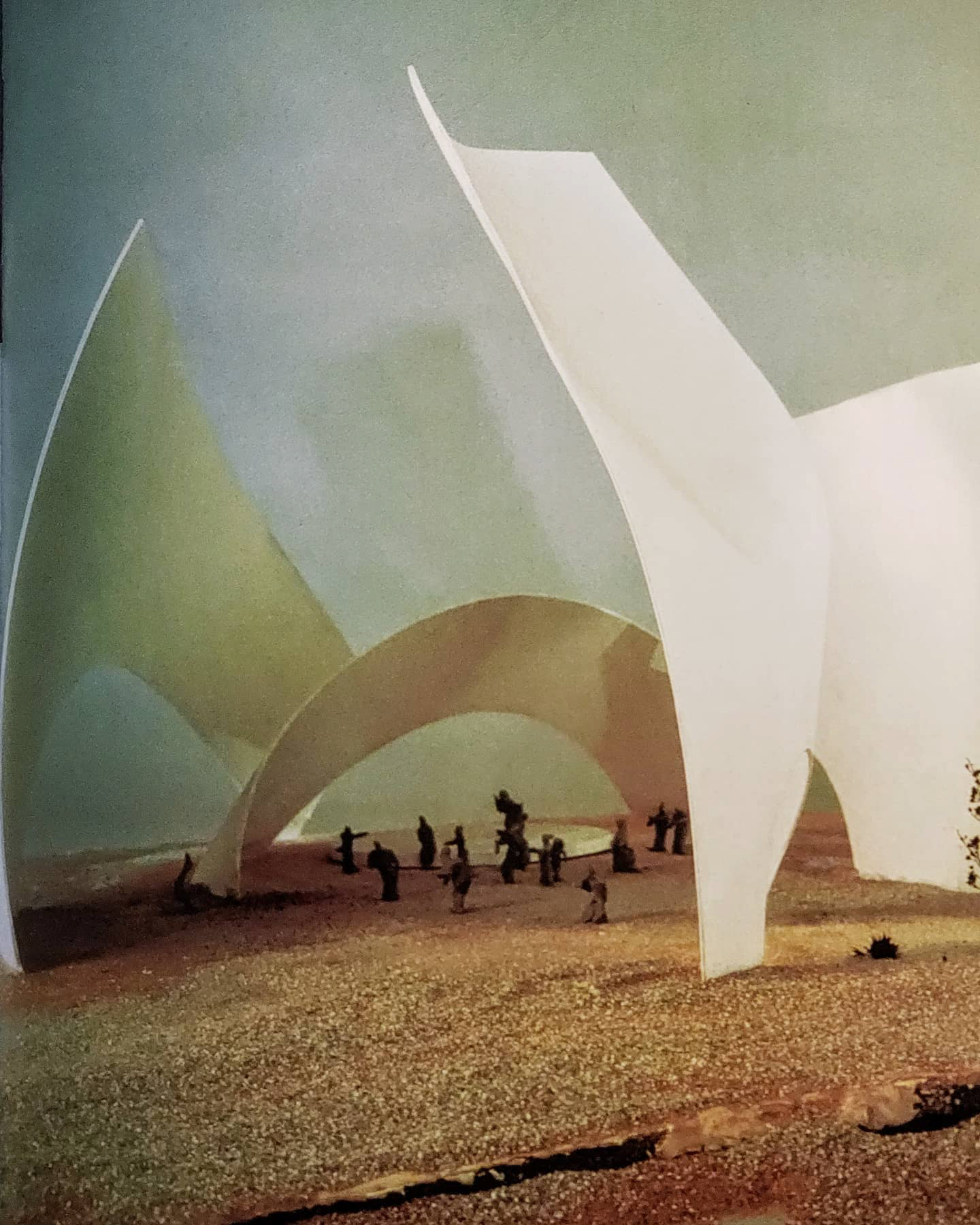 a photograph of a model with miniature figures under a large sweeping white arch