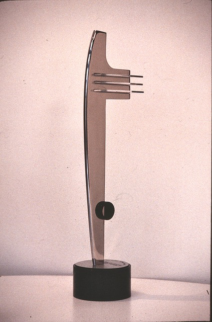 a slender vertical trophy that resembles the fender of an art deco automobile, chrome with a circular black base