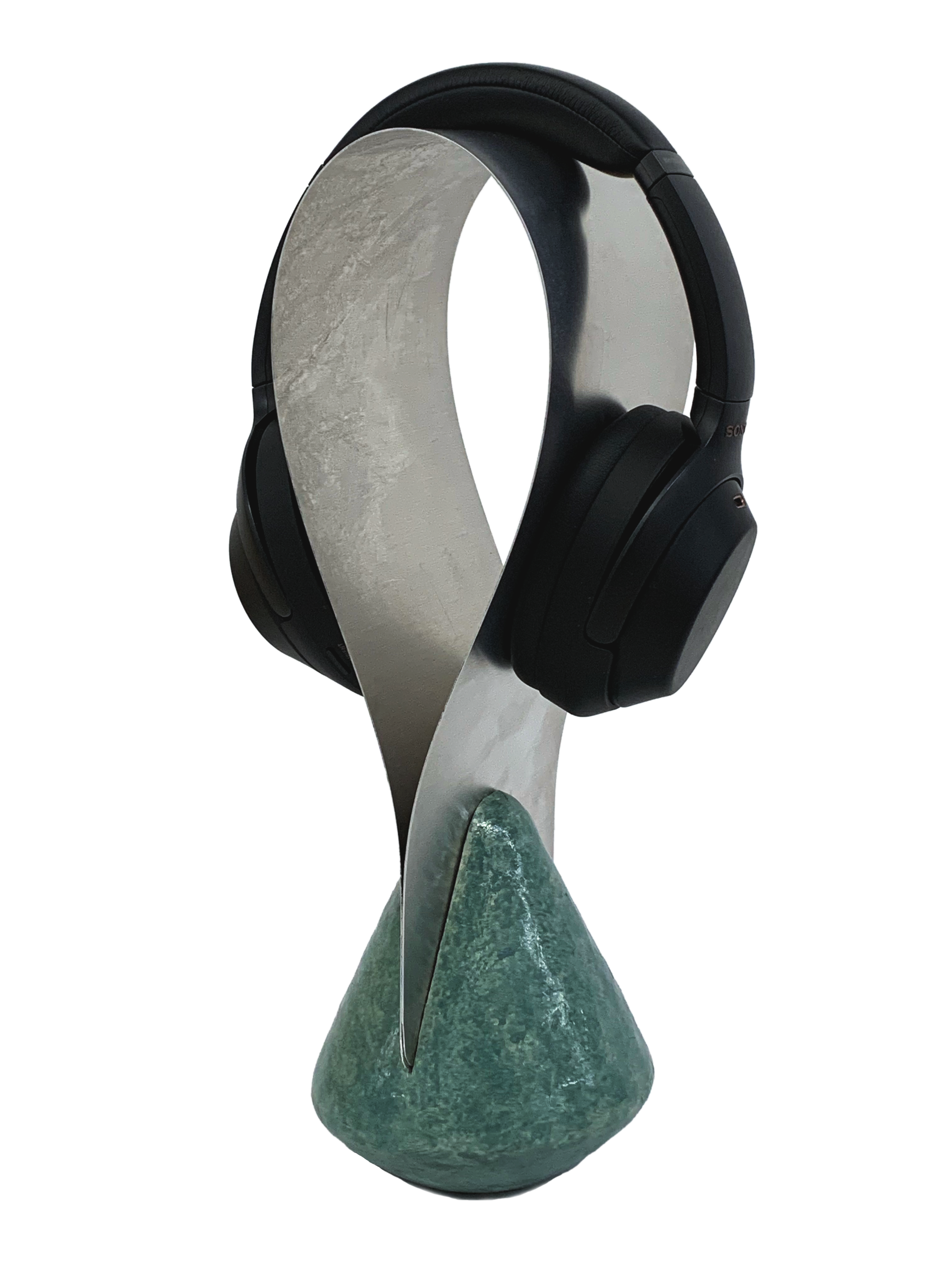 a curved metal plane with a green base that holds a pair of black over ear headphones