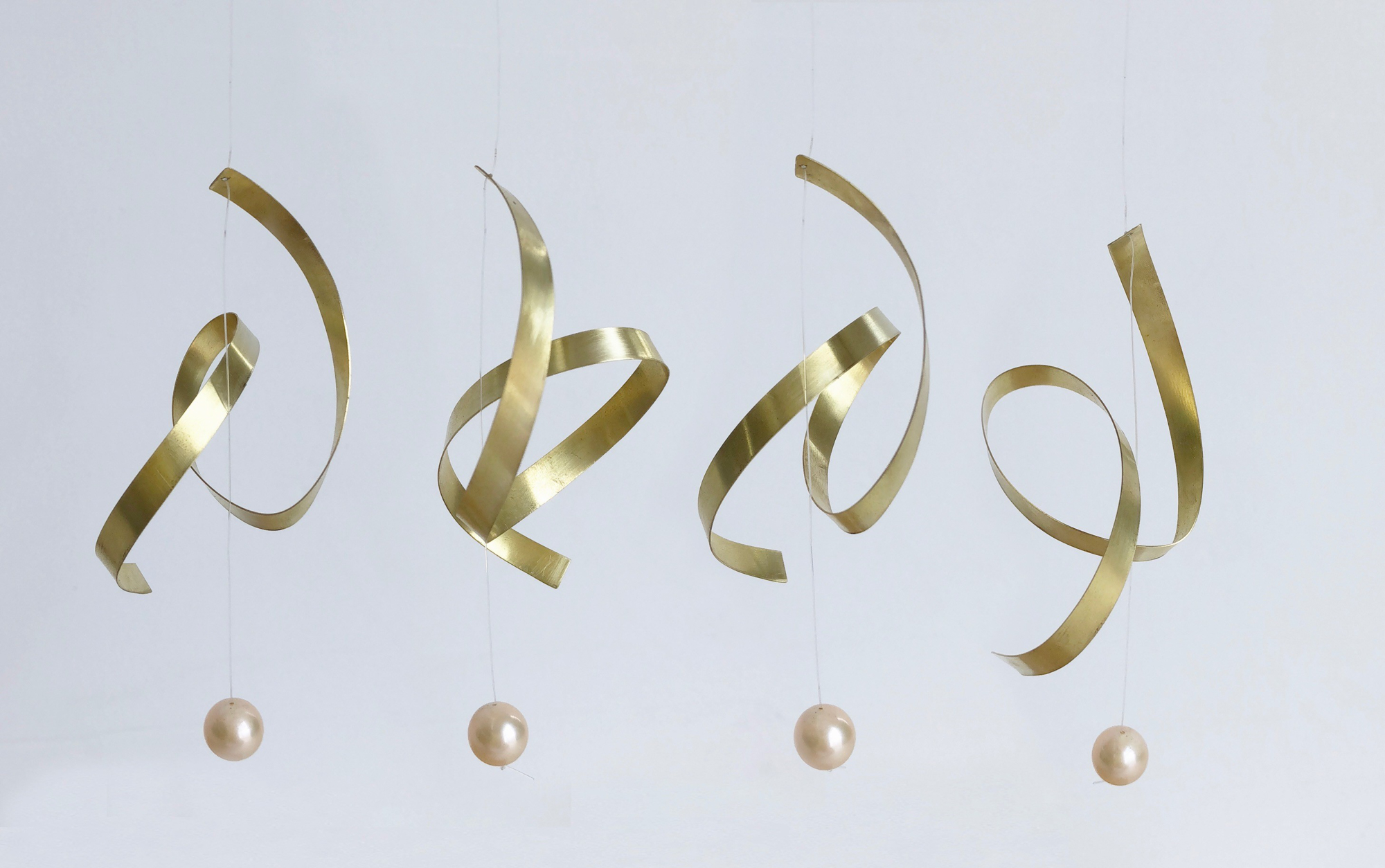 four golden earrings made of thin curved spiraling planes with spheres dangling beneath