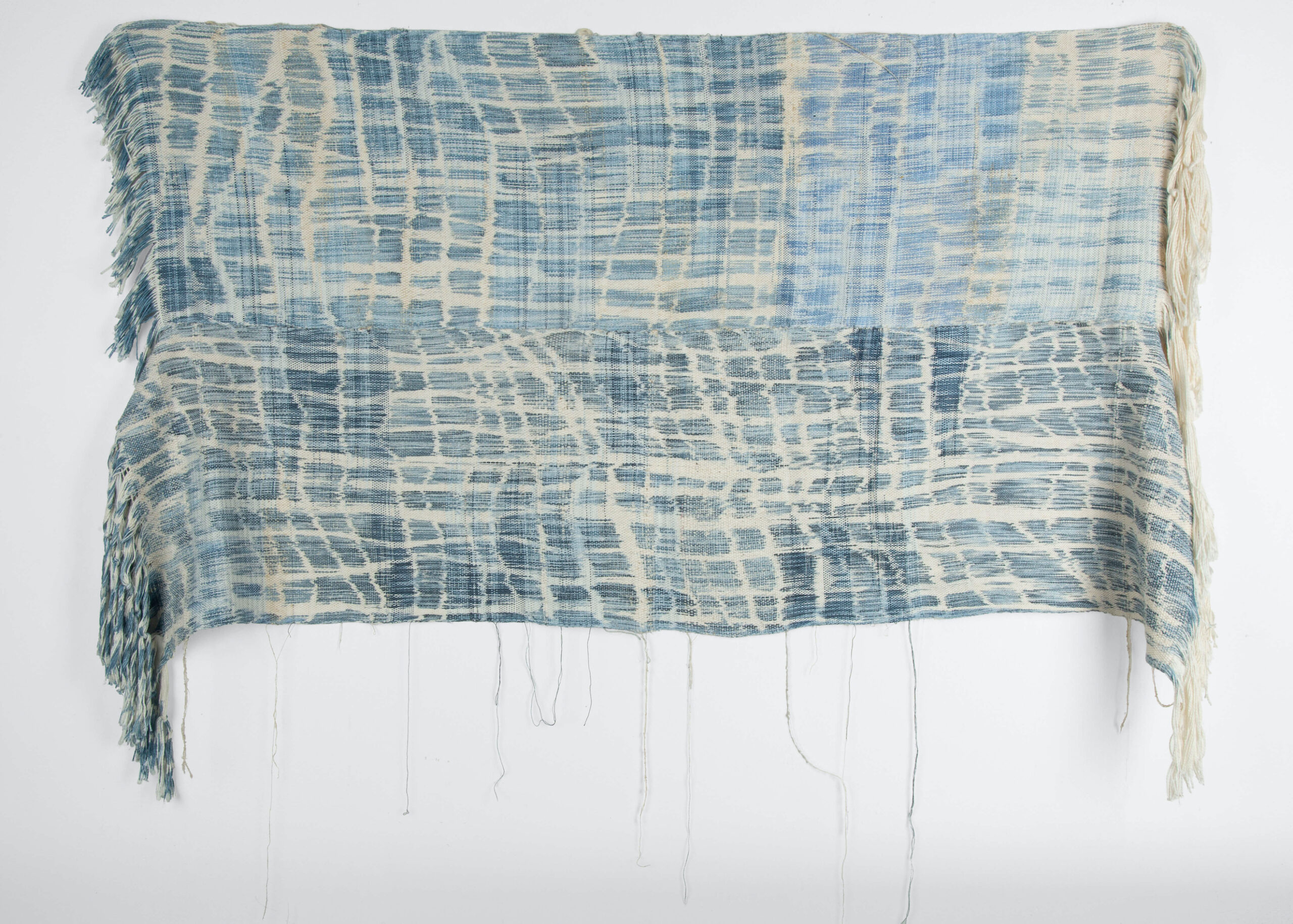 Woven tapestry using shades of blue and white fibers resembling pools of light and shadow on gently rippling water.