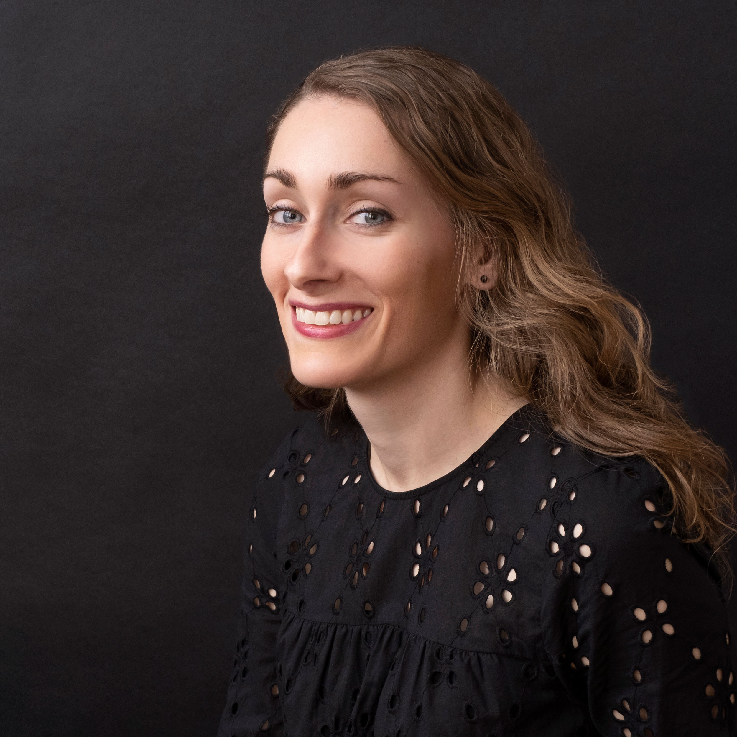 A portrait of a smiling Annie McLaughlin against a black background.