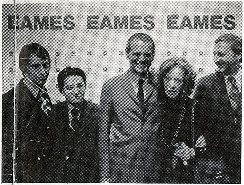 photograph of four men and one woman in a celebratory mood beneath a sign that says EAMES three times