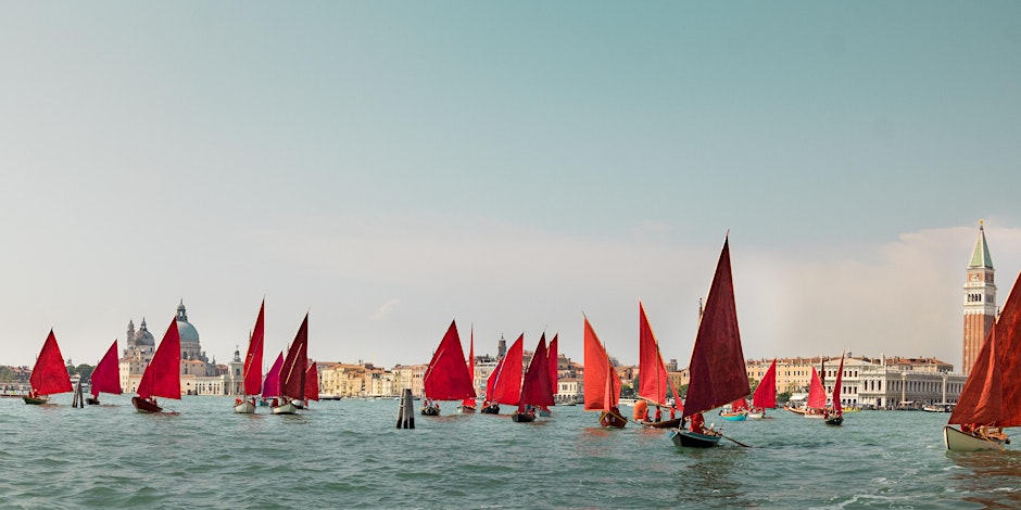 A picture of red sail sailboats in Venice, Italy.