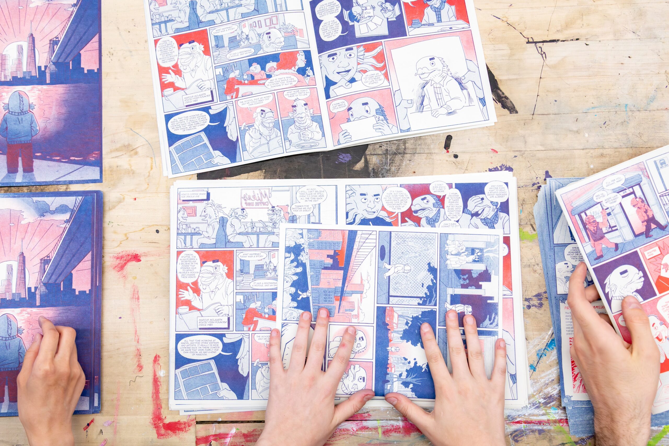 Printed pages of Static Fish comic club's anniversary zine, risograph-printed in red and blue