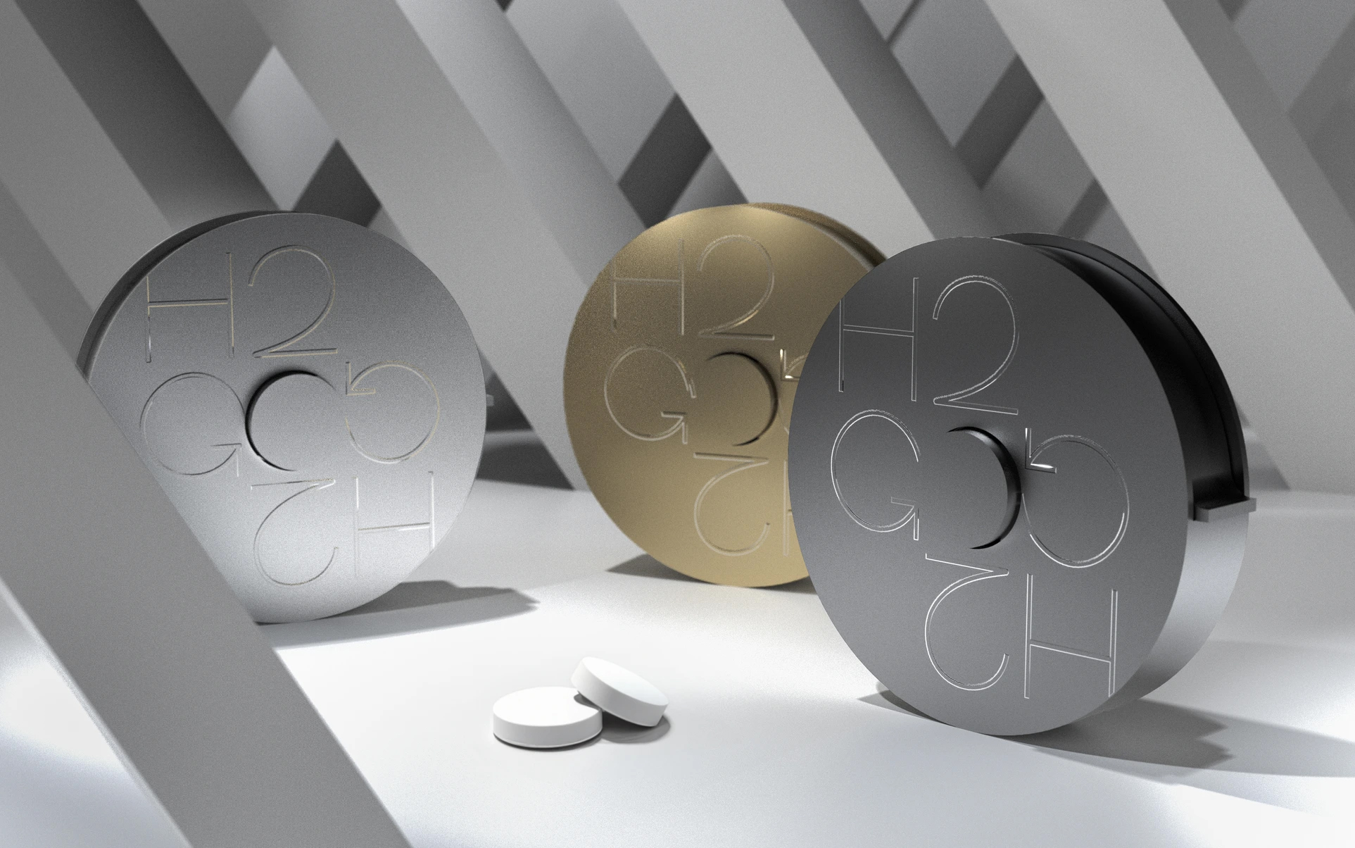 Three circular objects in metallic finishes (silver, gold, and black) with the inscription "H2G" prominently displayed. The objects are arranged on a light-colored surface, with two smaller white discs positioned nearby. The background features a geometric pattern of intersecting lines.