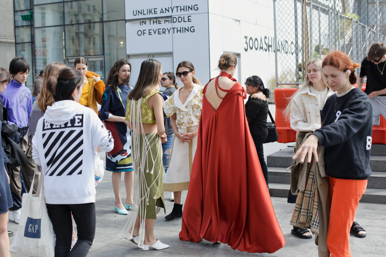 multiple models, standing on a city sidewalk wearing designs from students