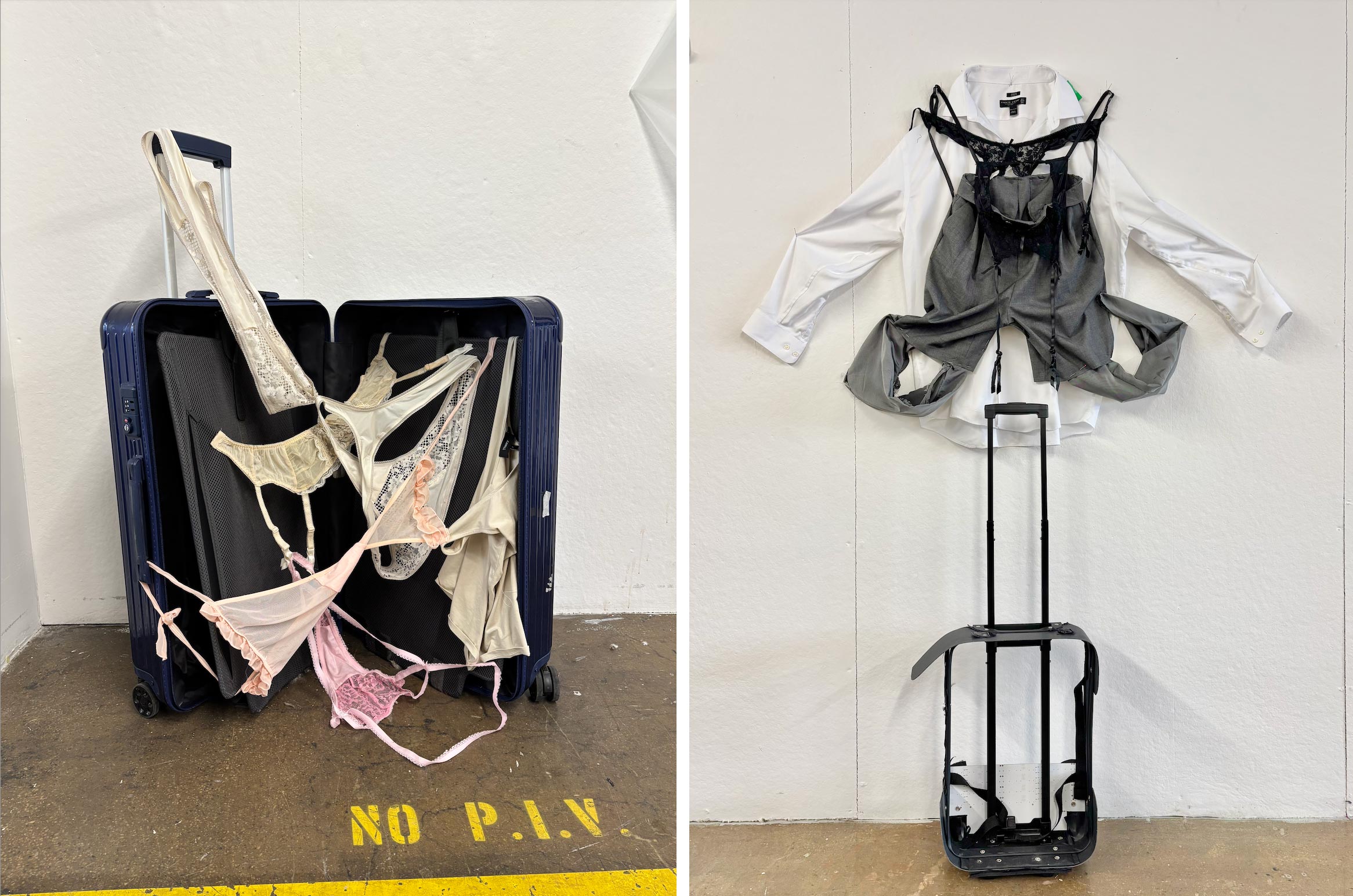 A navy suitcase is overflowing with various styles of lingerie, including light pink and beige pieces, spilling out onto a concrete floor. Adjacent to it, a white shirt and a grey jacket are artistically draped on a hanger, with straps resembling a corset attached, creating a unique fusion of clothing and suitcase elements. The background features a plain white wall with a warning sign on the floor.
