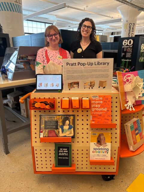 Alums Alex Austin (MSLIS '22) and Elizabeth Berg (MSLIS + MAHAD '15) run a Pratt Popup Library at this year's Research Open House