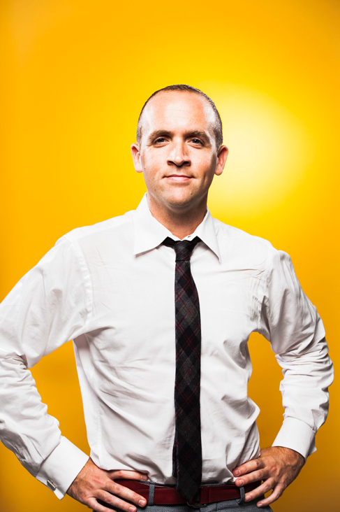 Dean Cocciolo stands in front of a yellow background.