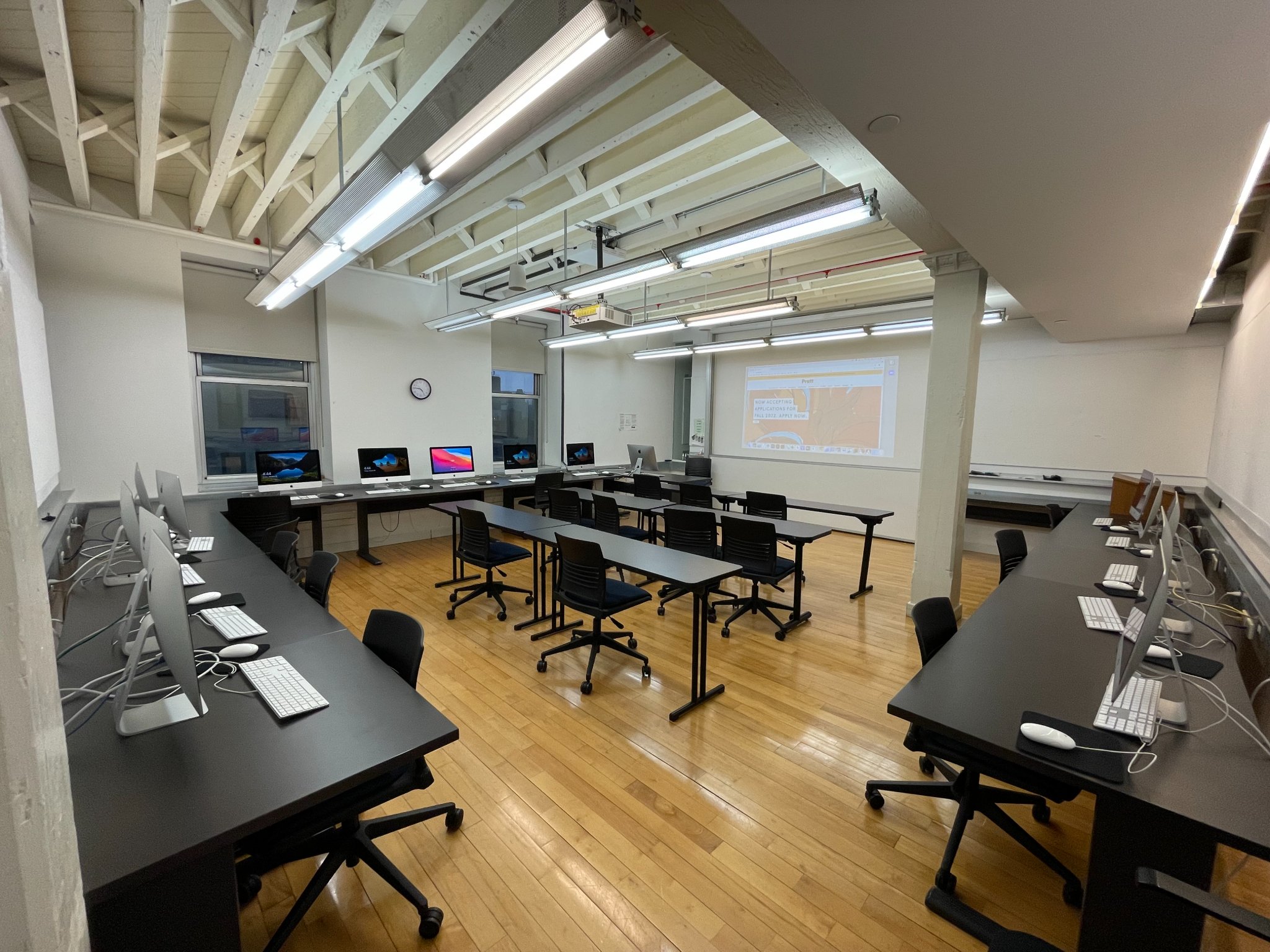 An array of work tables, some with computer workstations others just with chairs.