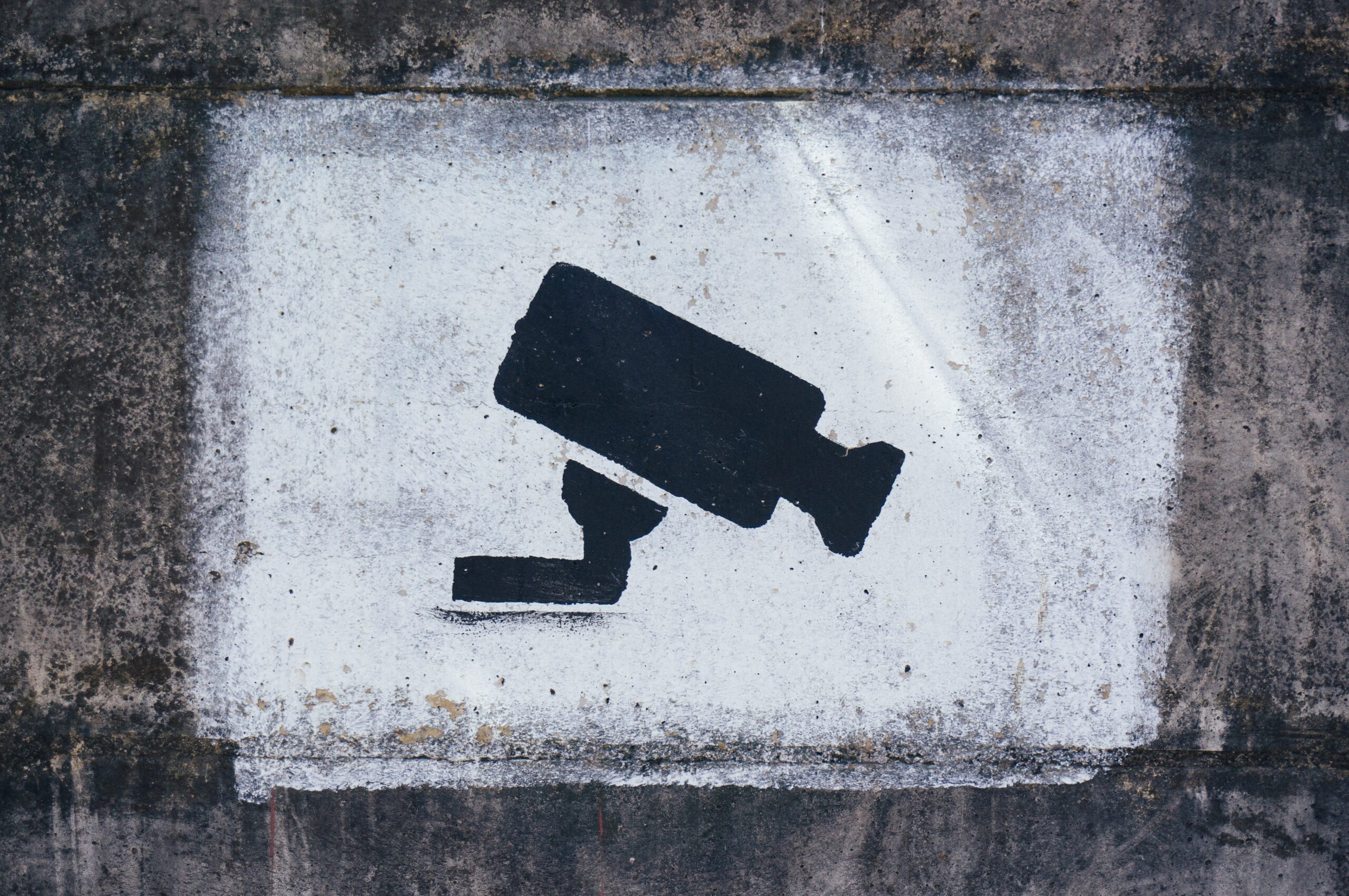 Surveillance camera stencil spray painted on a concrete wall