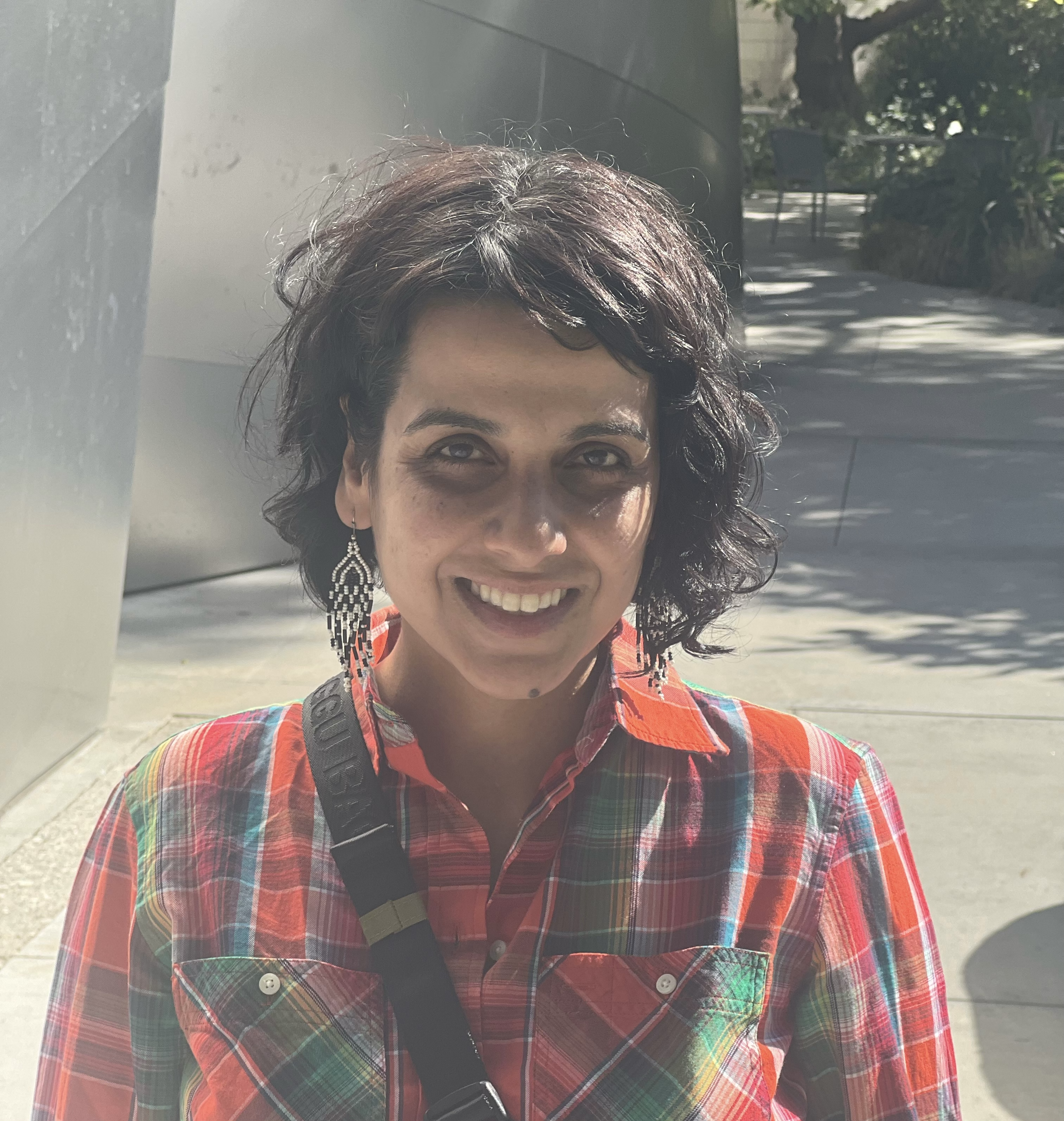 headshot of Karin Shankar, standing near concrete pillars