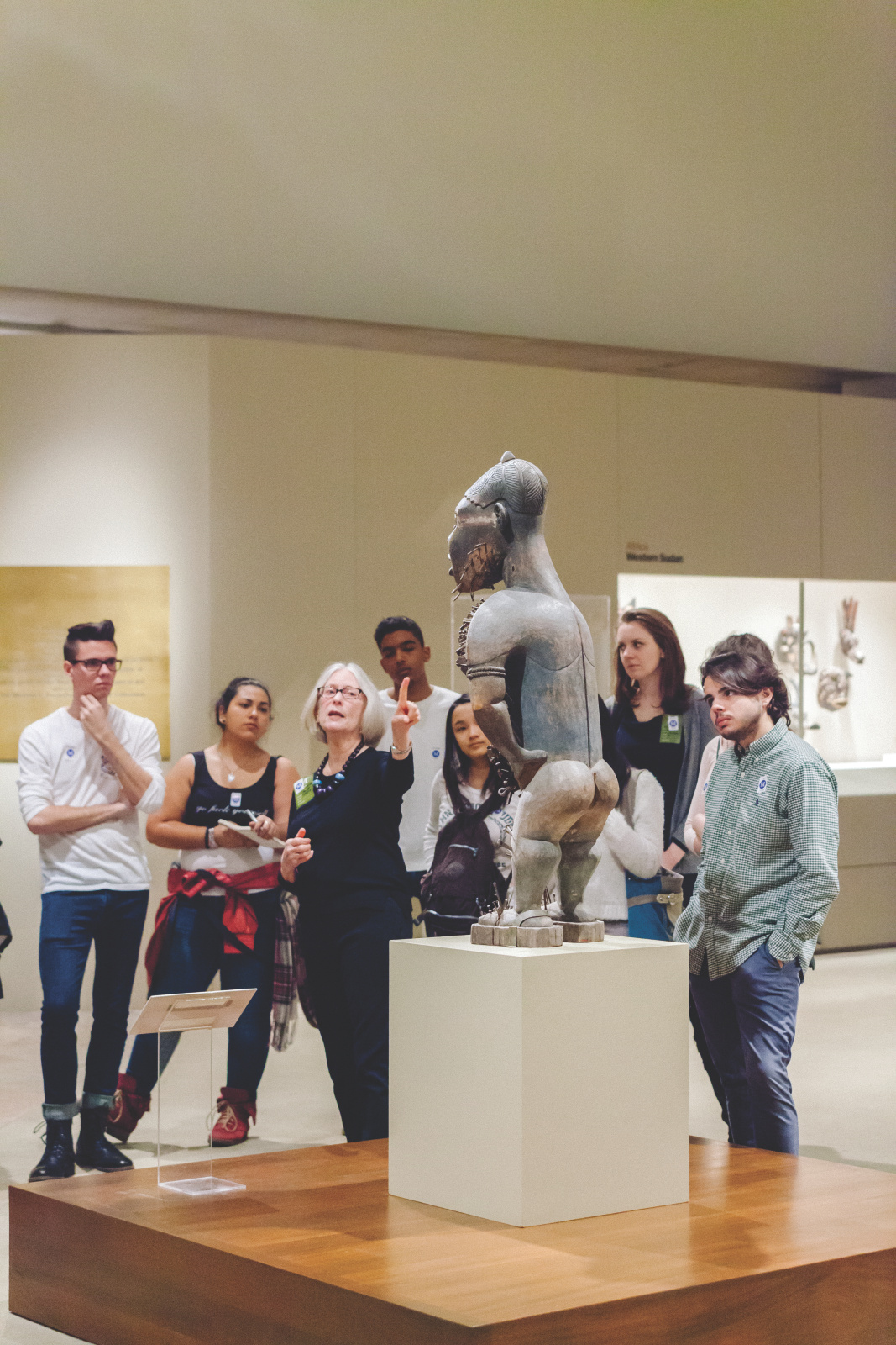 Students and teacher discuss a piece of African figurative sculpture.