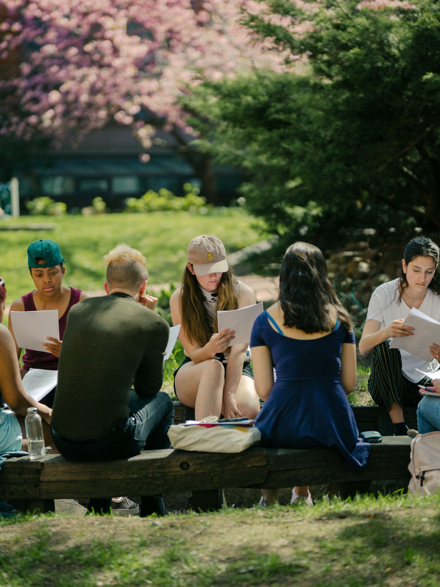 students sitting side by side reviewing some work on a lawn