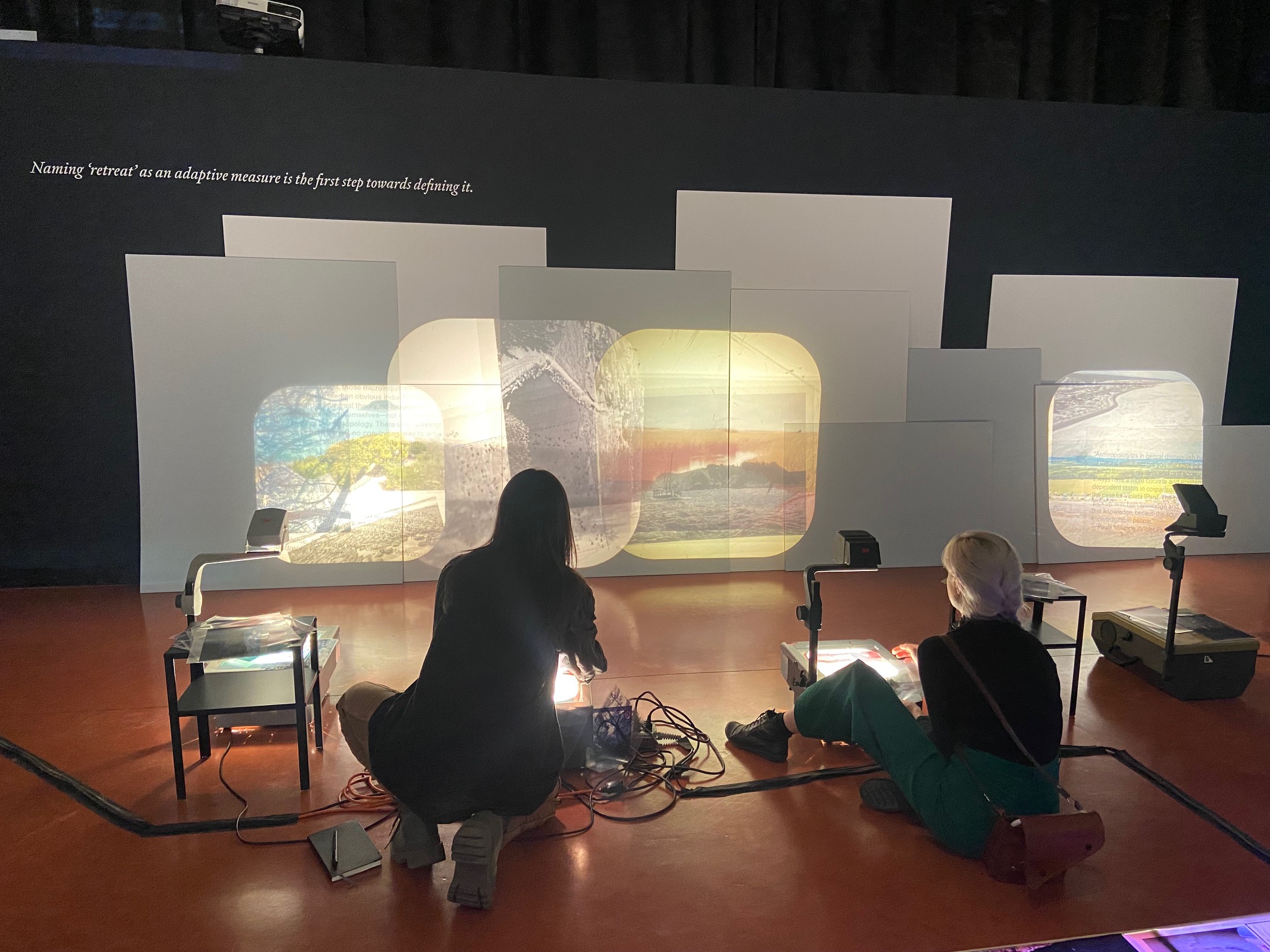 two people crouching on the ground in front of a video projection art piece