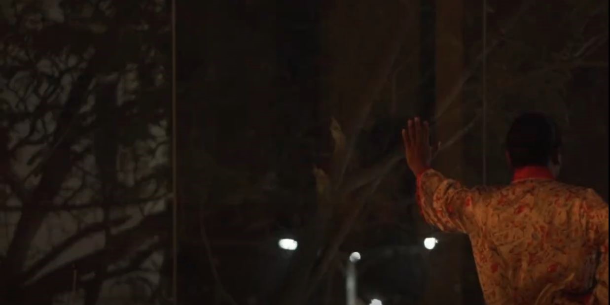 a man in red leaning against a window