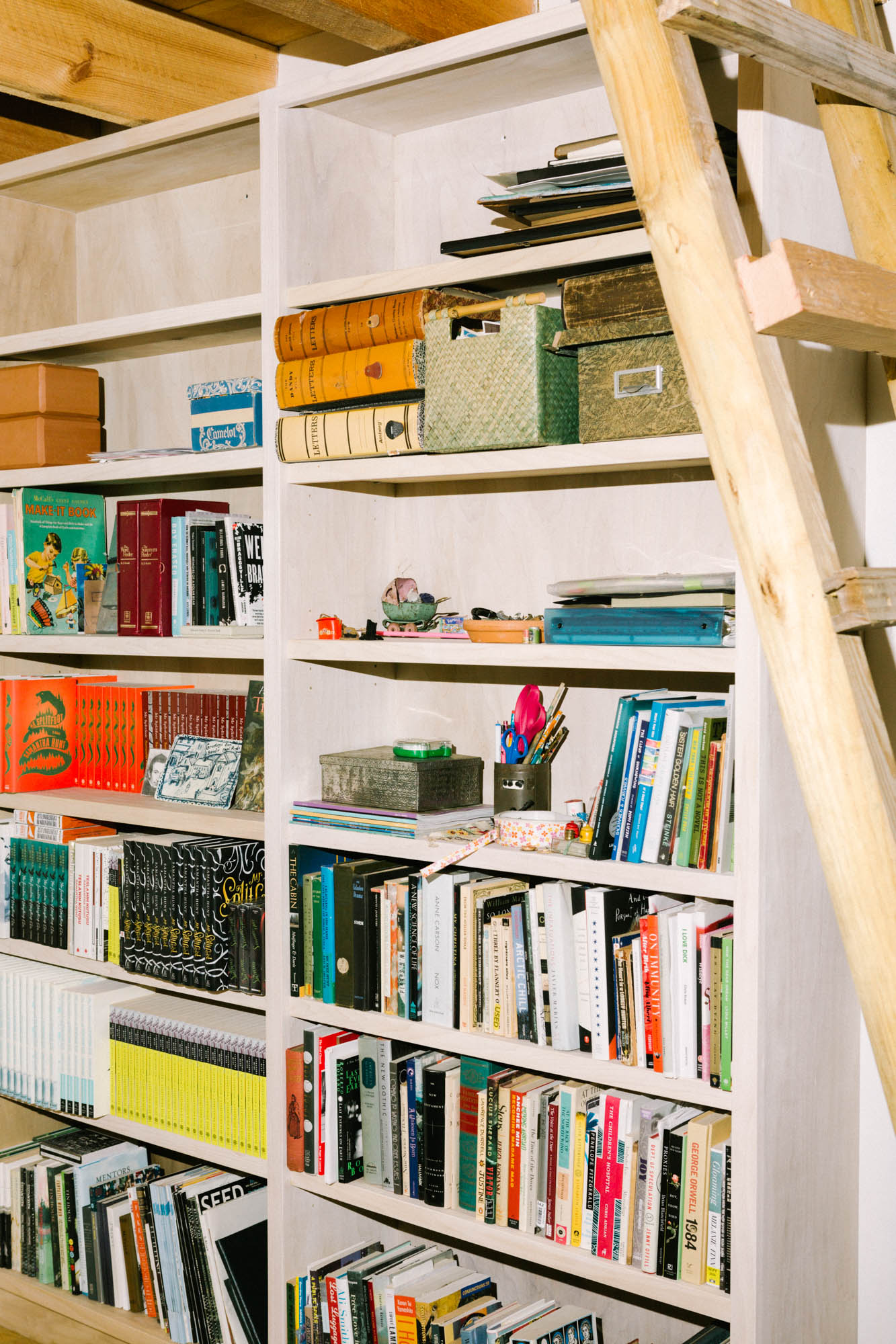 A white bookcase with books lined in the walls in Samantha Hunt's studio.