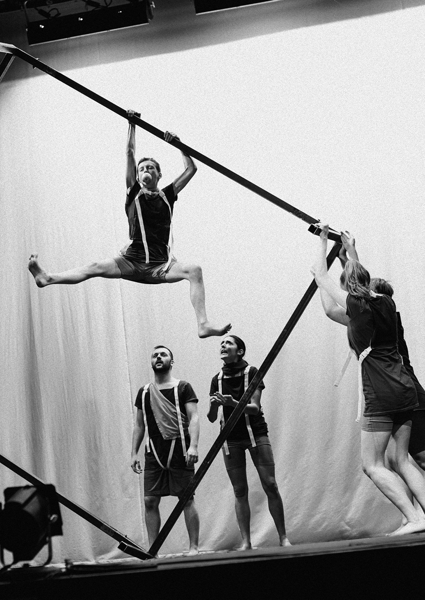 Performers climb on and handle a large rectangular object onstage