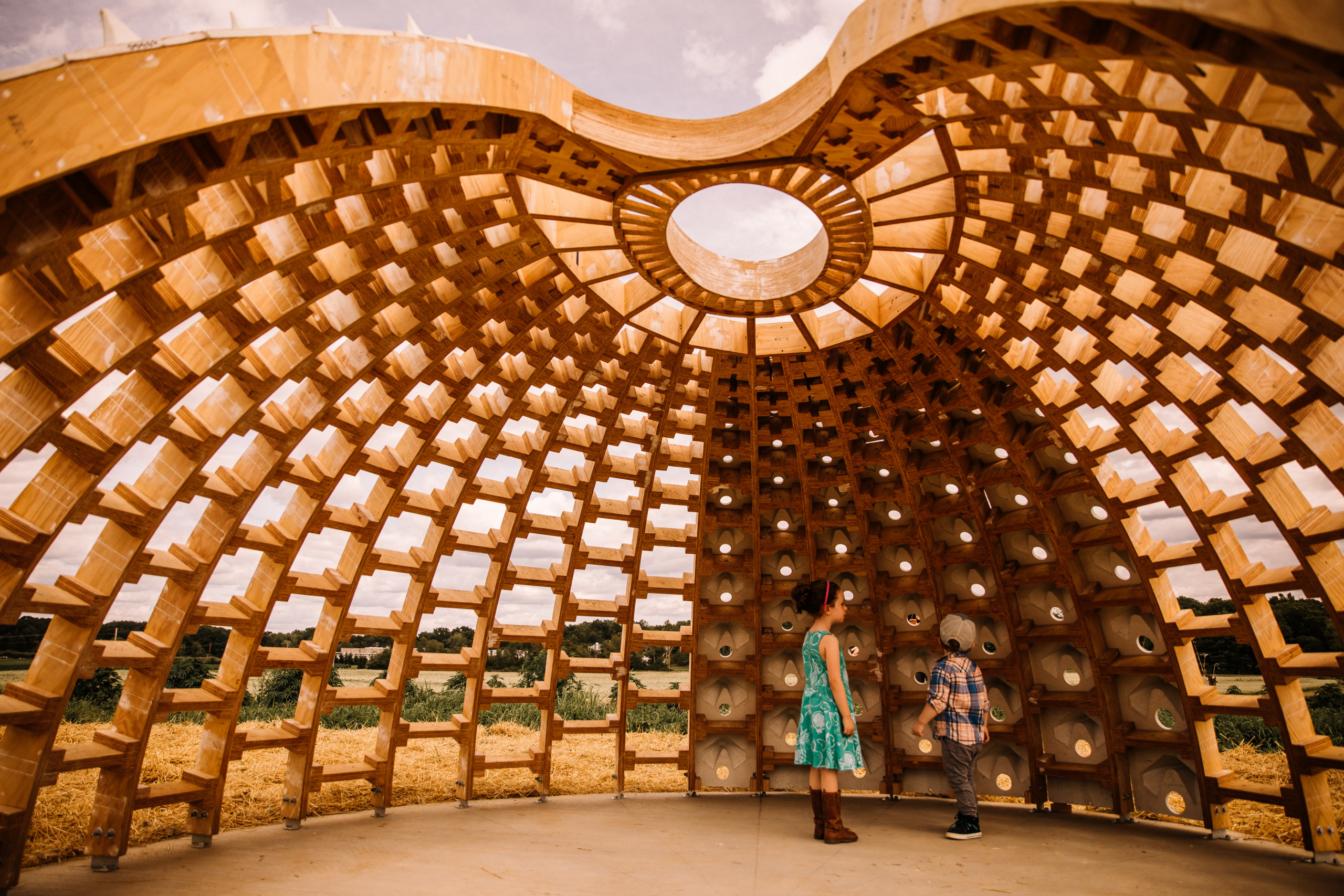 Children stand within a dome in construction with a honeycomb pattern