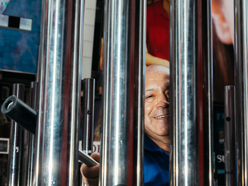 picture of a man behind hollow metal bars, he hits the bars to make a sound
