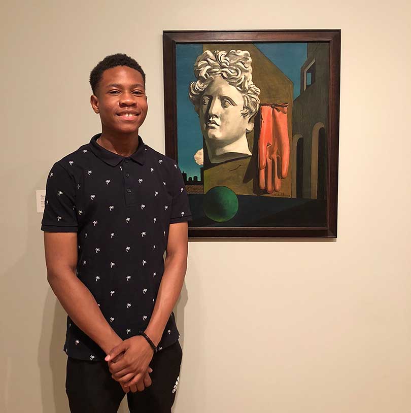 Picture of Ajani Stewart posing with his artwork