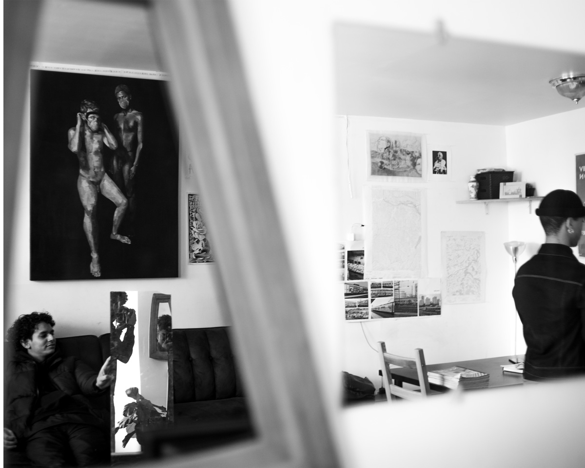 Picture in black and white of two men, one facing the other; the other facing away.