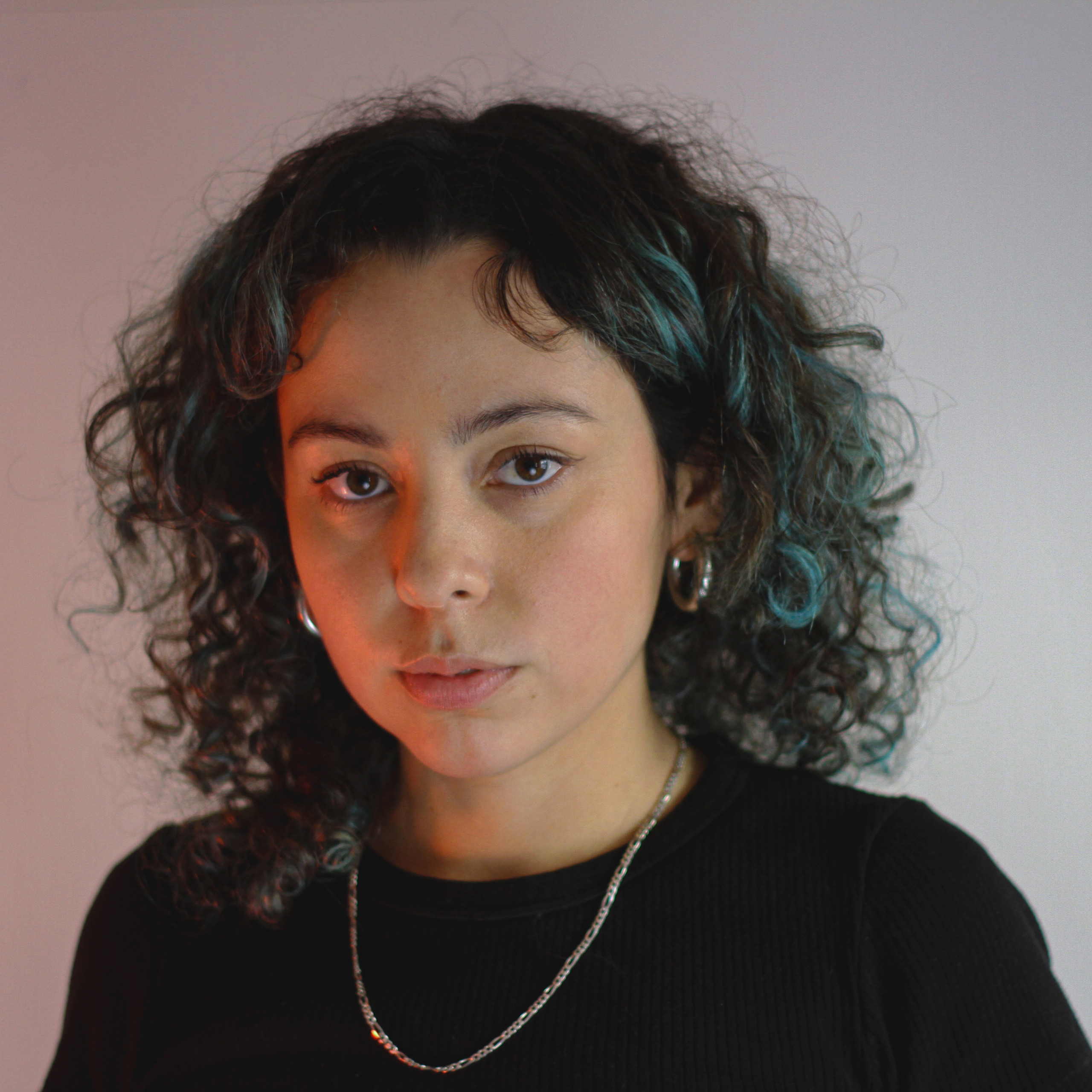 Headshot of Valentina Vergara, with dark brown and teal curls, silver chain and hoop earrings, against a rose and lavender gradient background