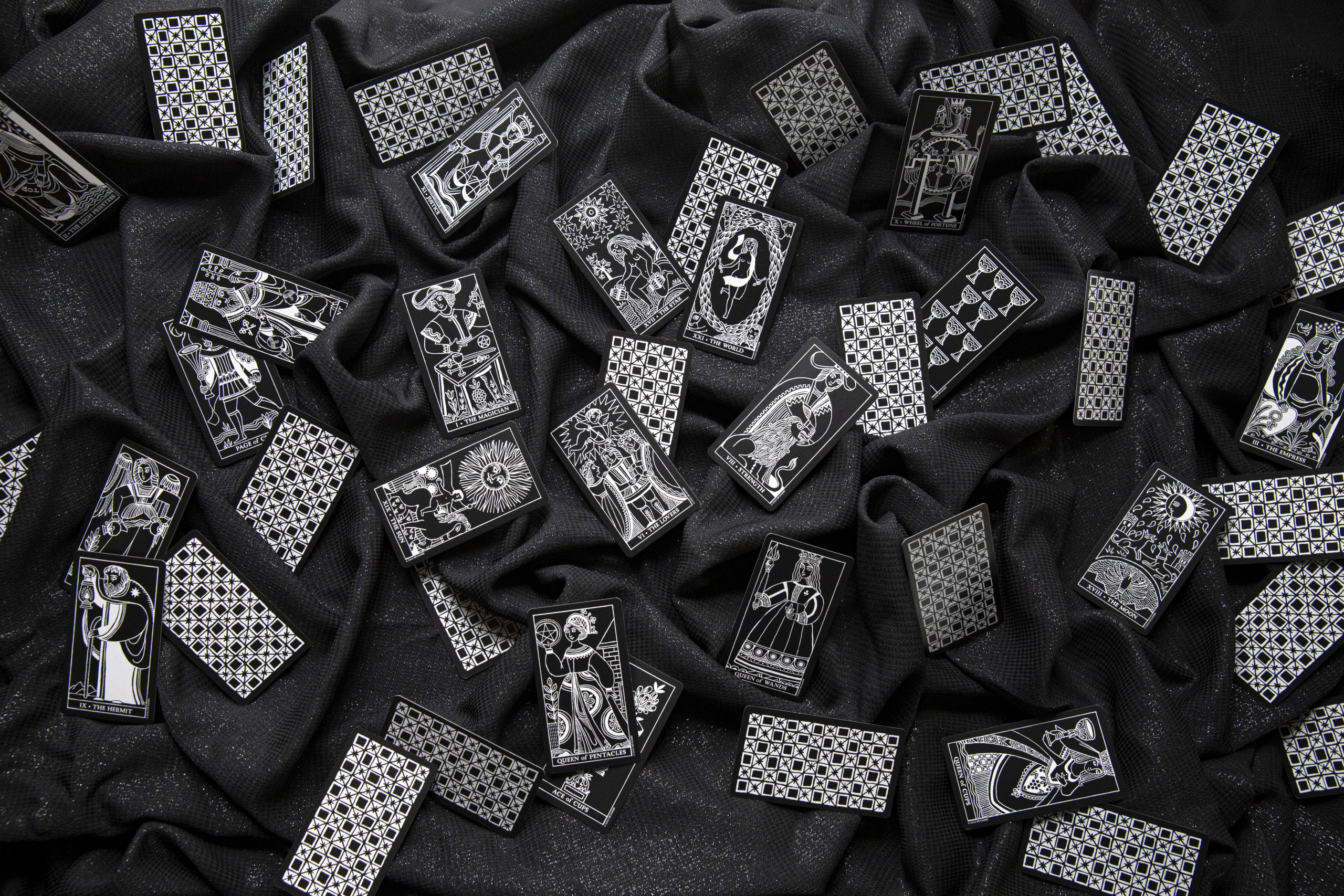 Black and white tarot cards spread across a glittery black cloth