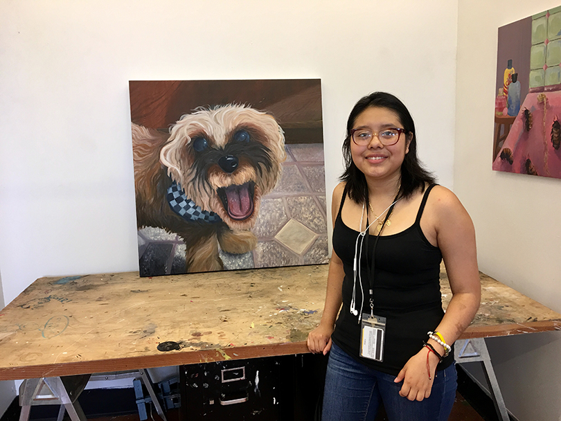 Picture of Mariel Hernandez posing with her artwork