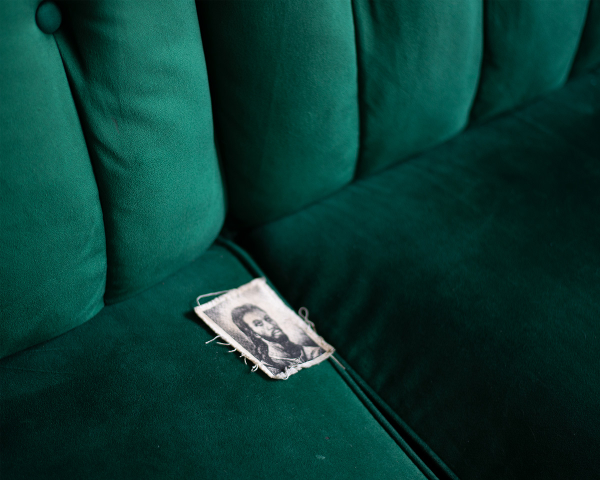 Picture of man with long dark hair and beard on a green velvet seat.