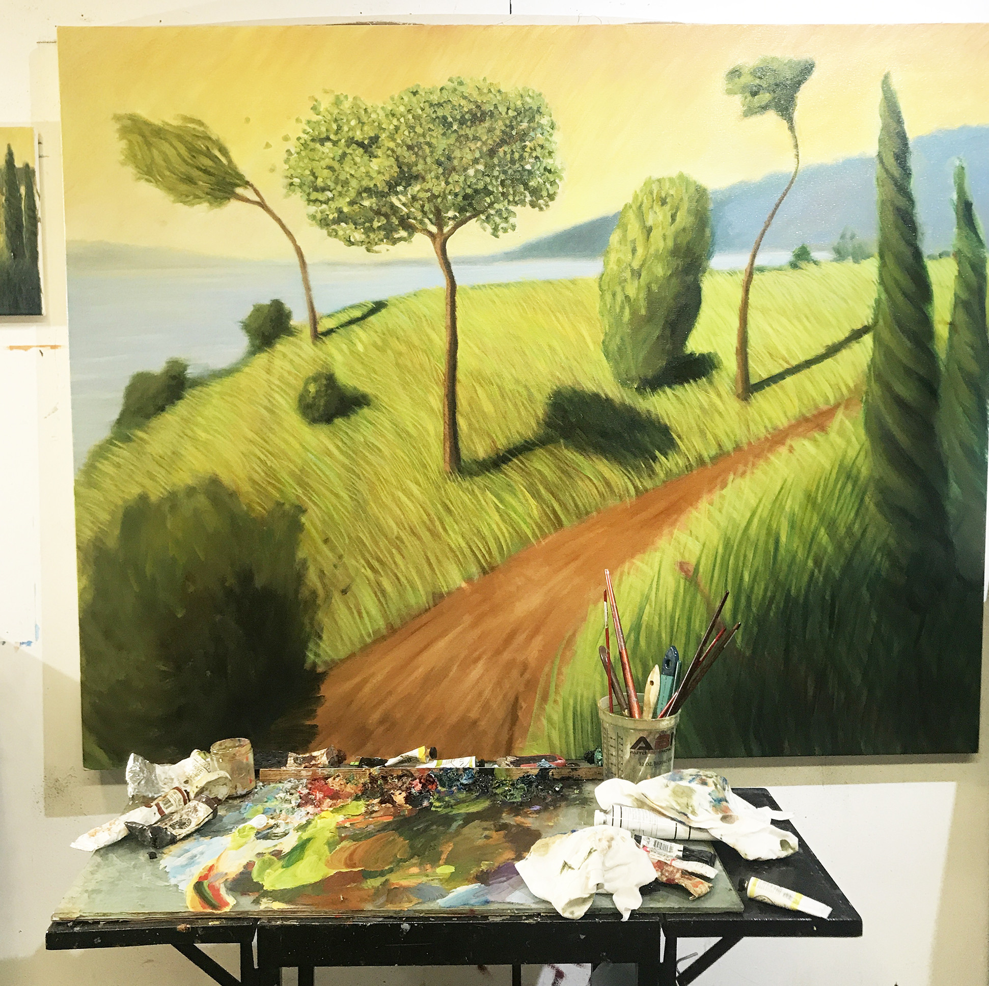 Painting table in front of a painting with trees and a path