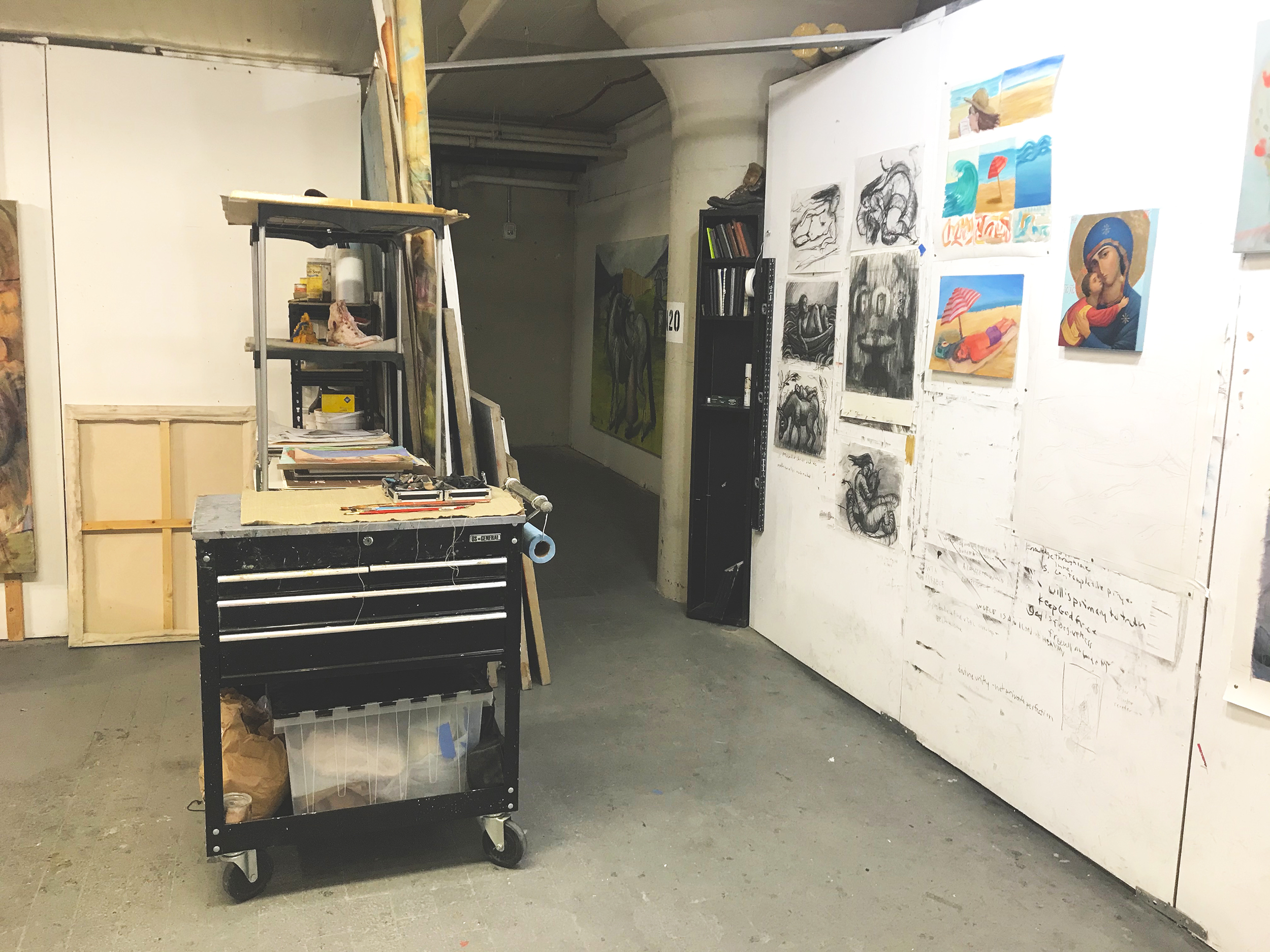 Interior of an artist's studio with work cart and paintings on a wall
