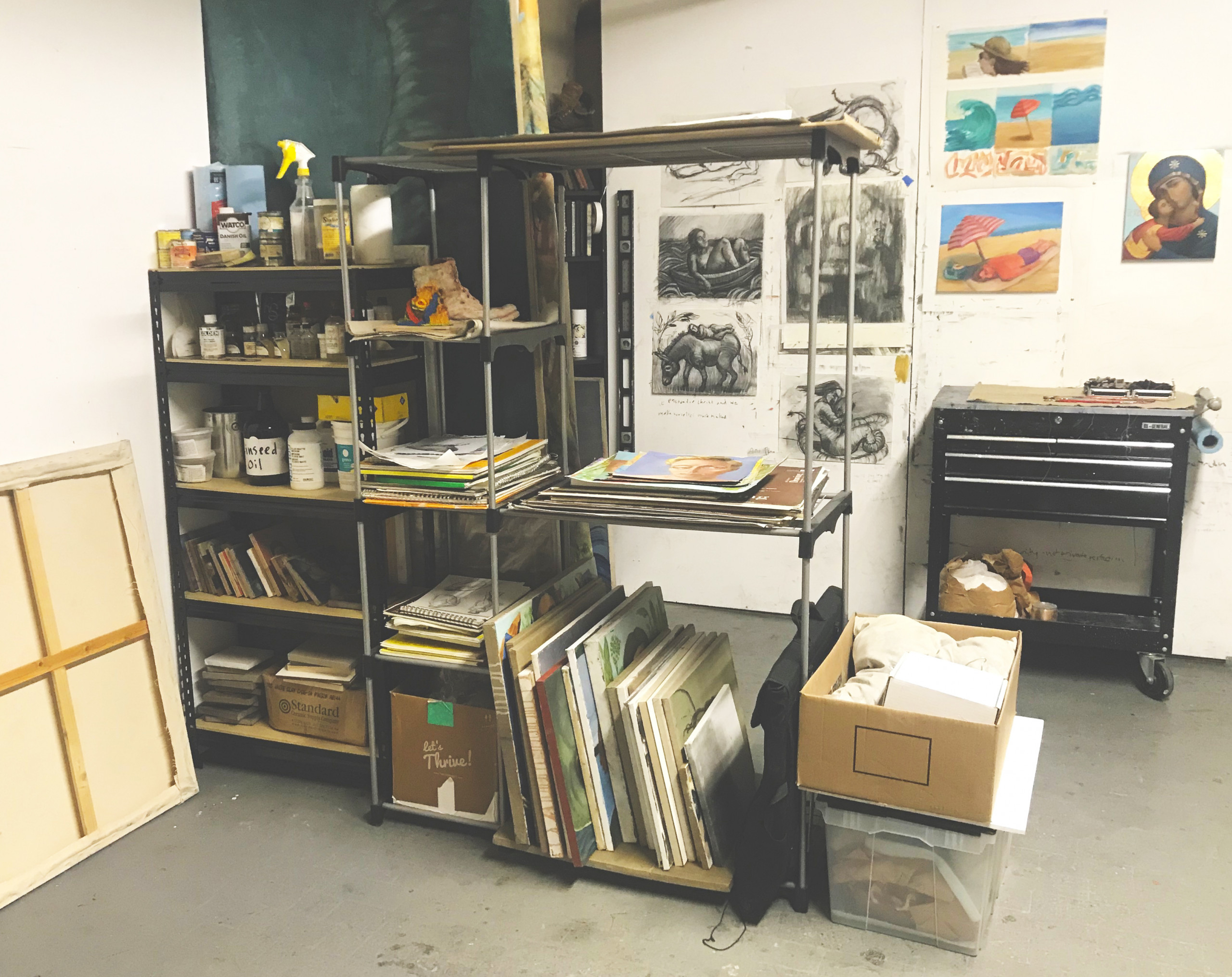 Interior of an artist's studio with shelves and paintings on a wall