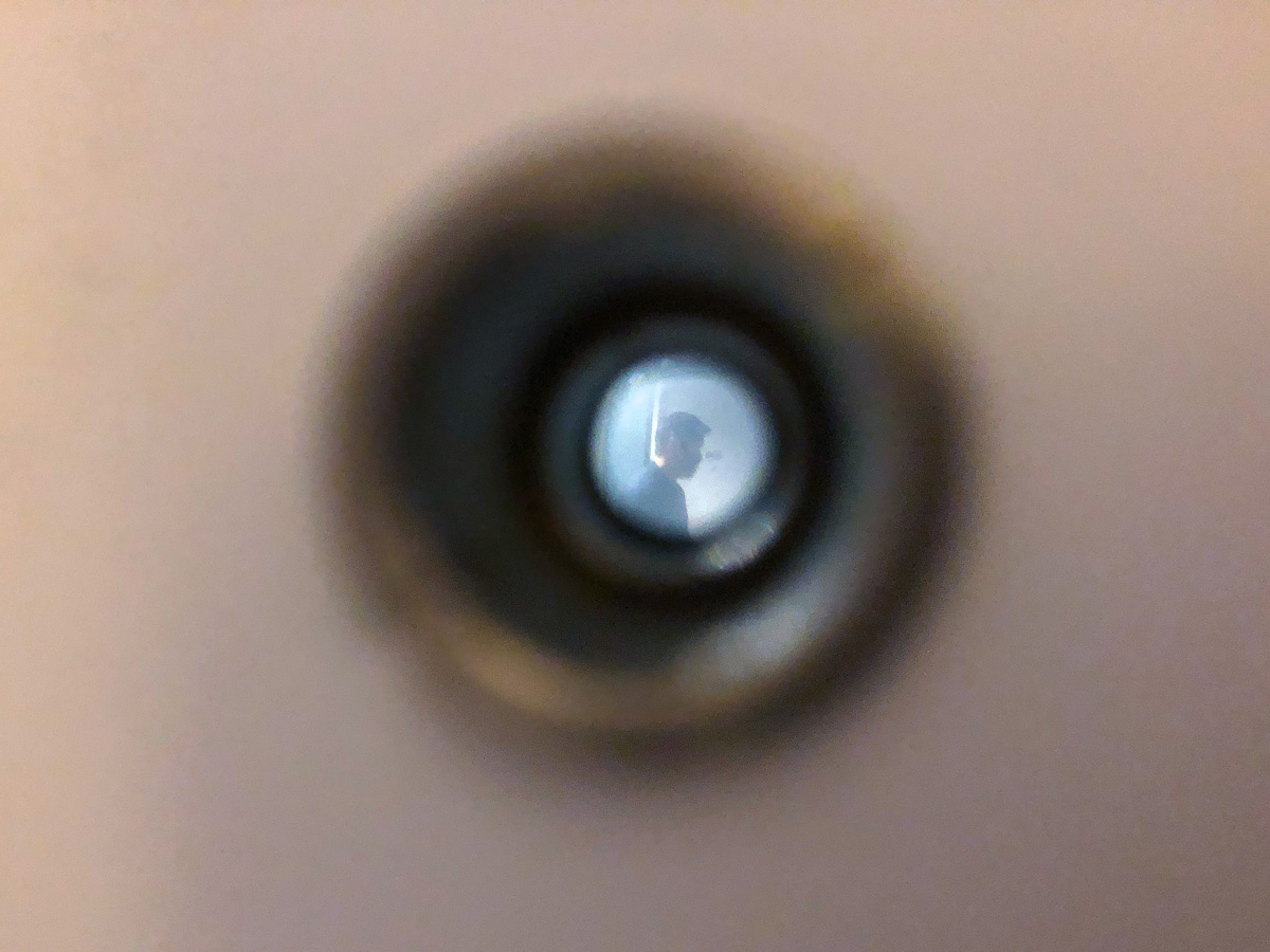Picture of a person through a peephole on a door