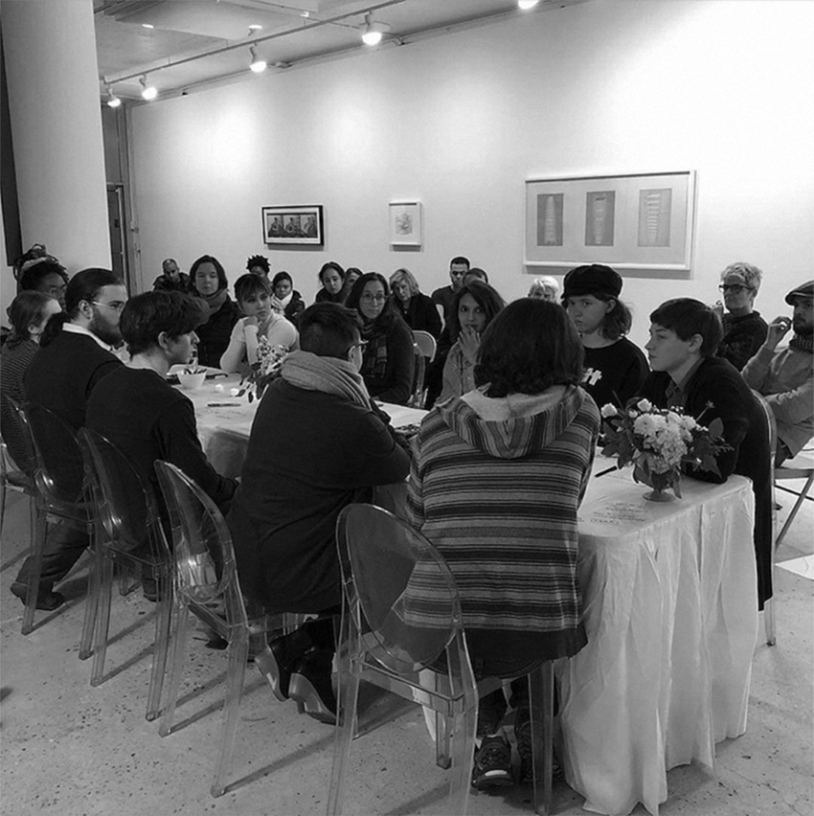 Students and faculty sit around a table in DeKalb Gallery