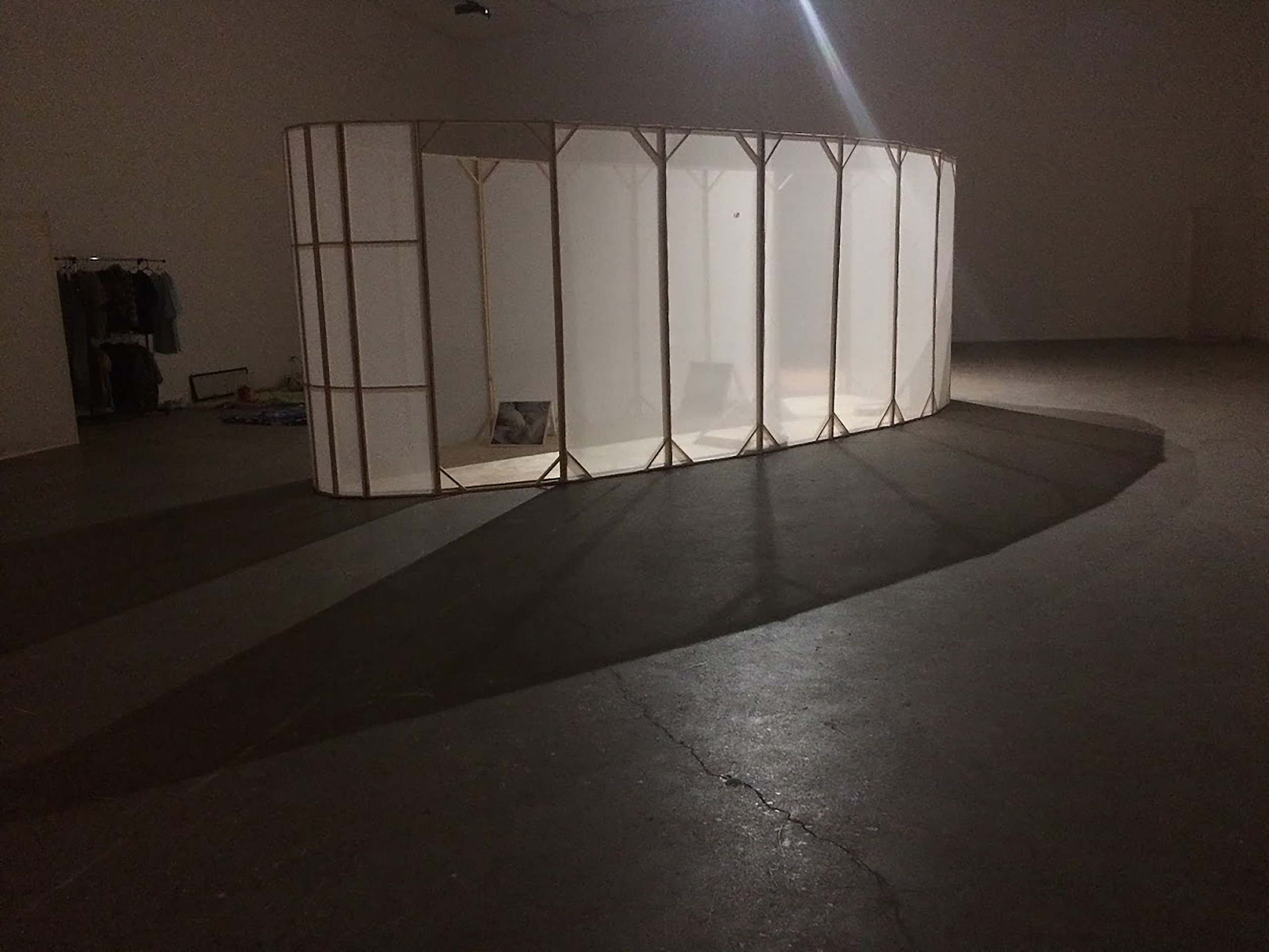 An oval structure with translucent walls casts a shadow inside a room lit from a single angle