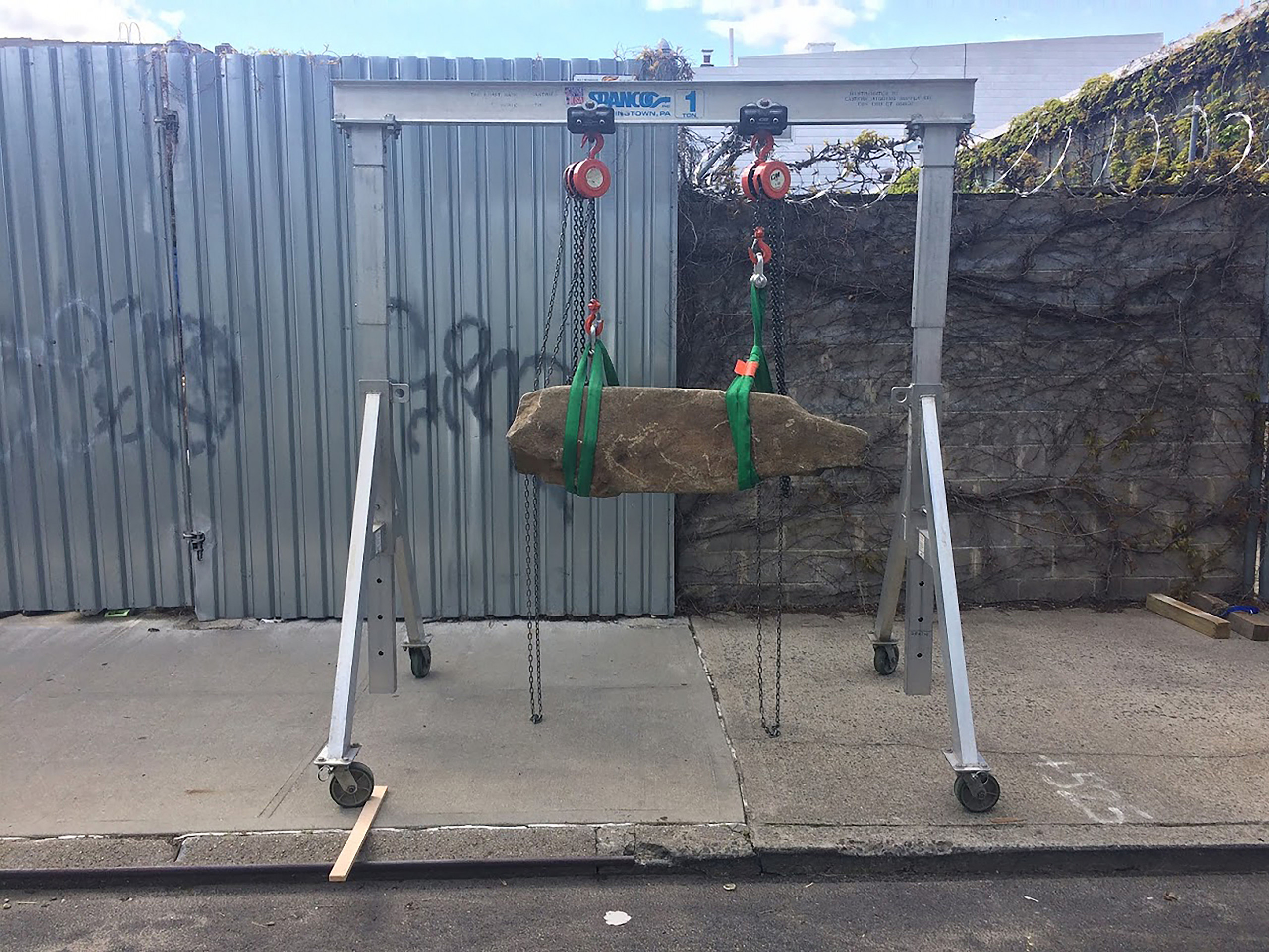 A stone suspended by pulleys on a metal frame
