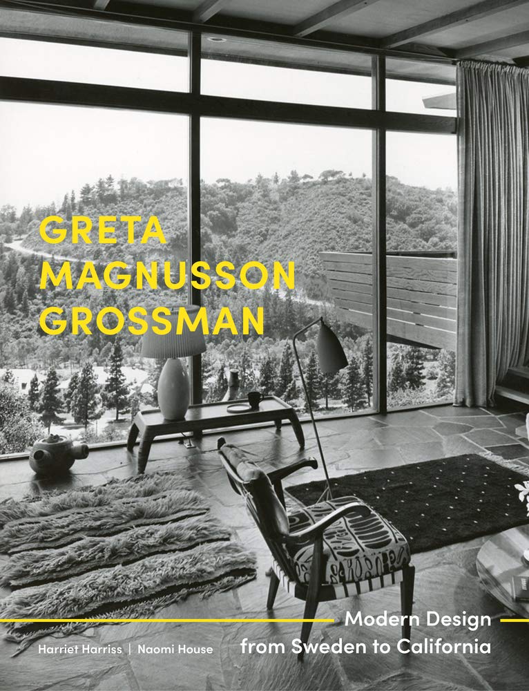 Book cover showing interior with plush rugs, stone floors, and view through floor-to-ceiling windows of a forested hillside