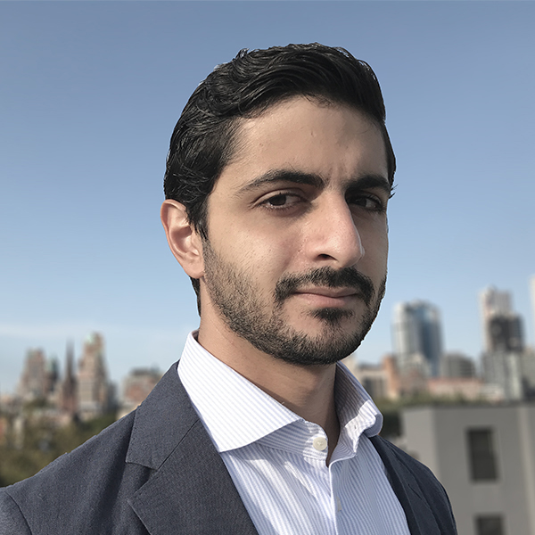 Headshot of Ahmad Shaibani, wearing white button-down and gray suit jacket