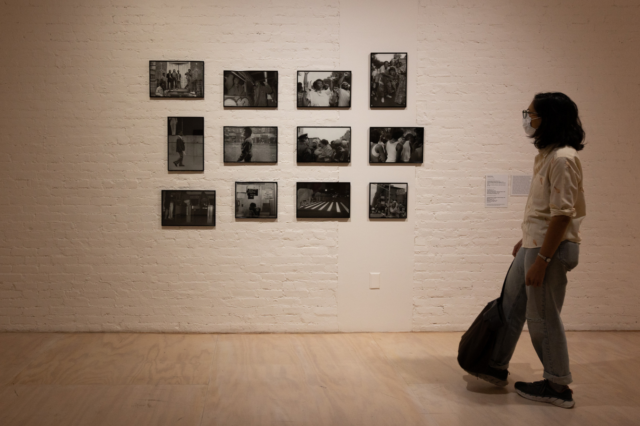 Museum visitor looking at installation of twelve grouped photographs
