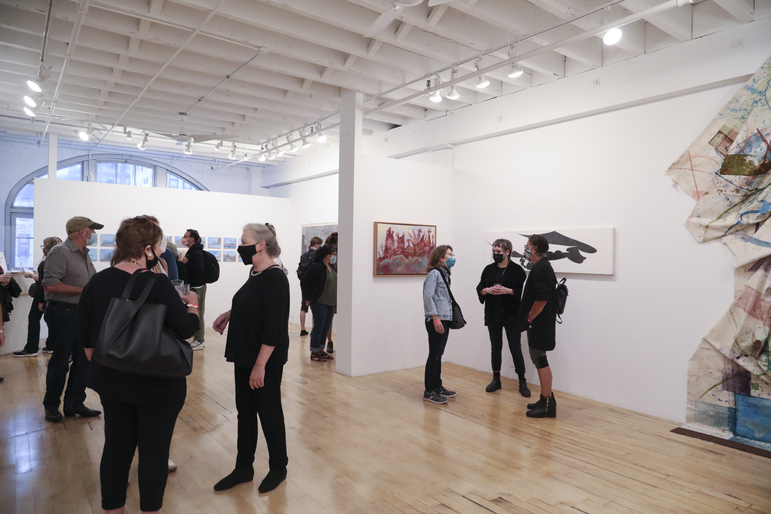 Gallery visitors converse amid various works