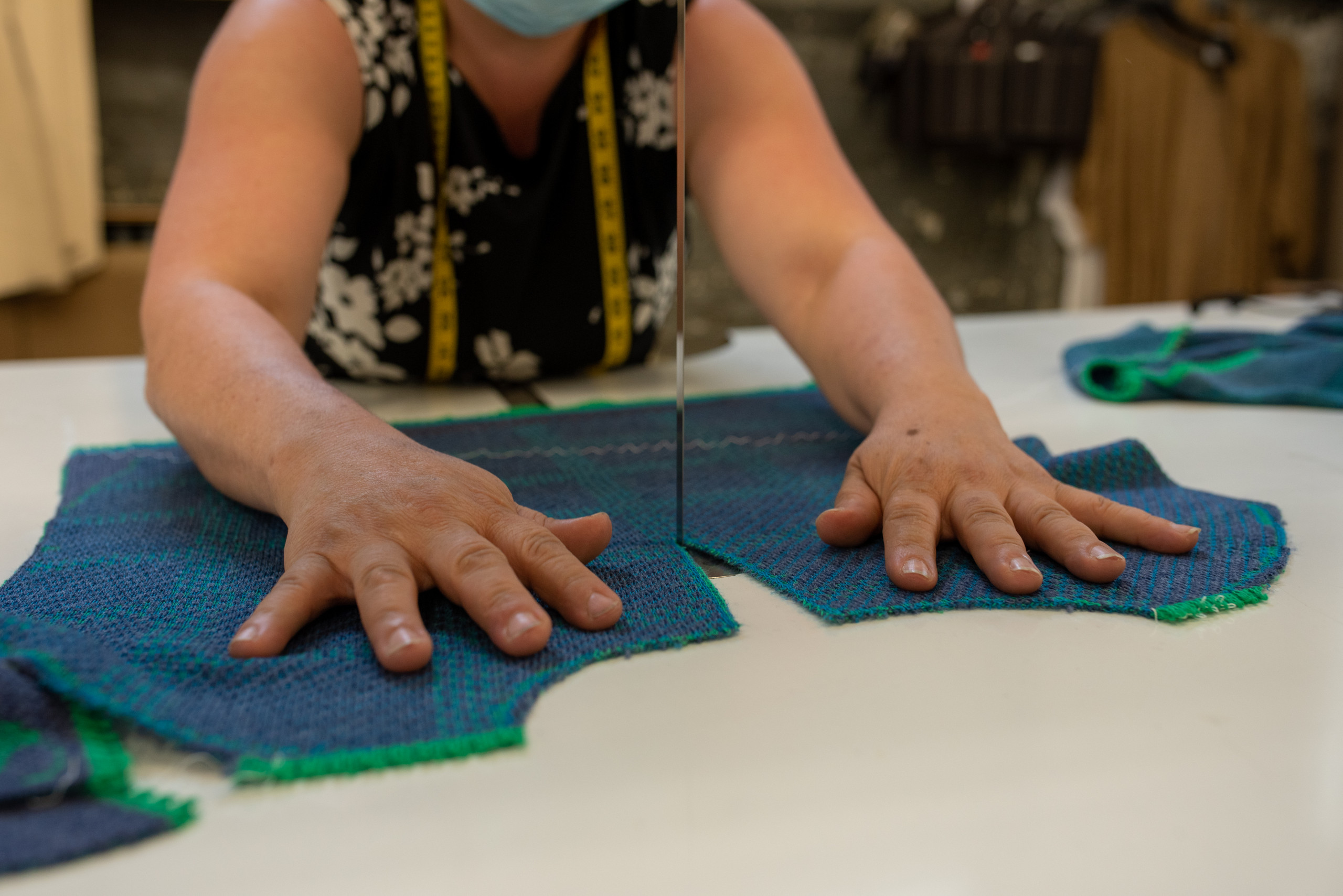 Hands guiding a knit green and blue panel