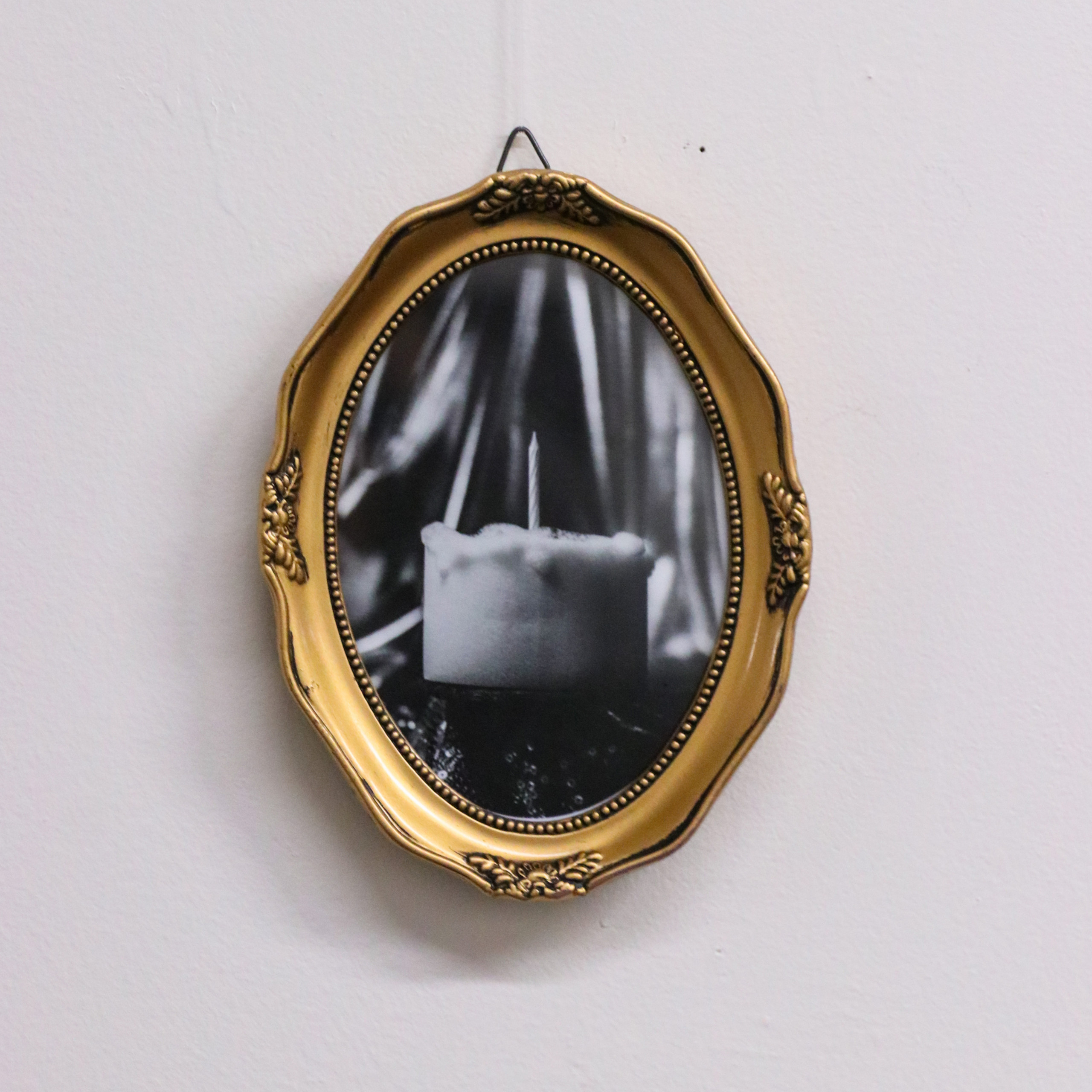 Oval painting with abstracted black-and-white forms within golden frame