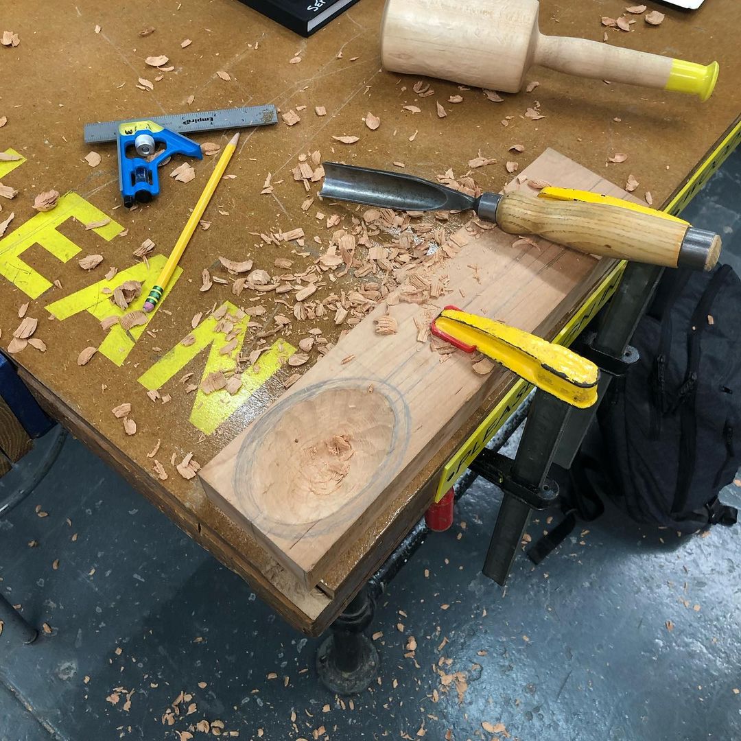 Work table with clamped wood block in the process of being carved, with scattered shavings