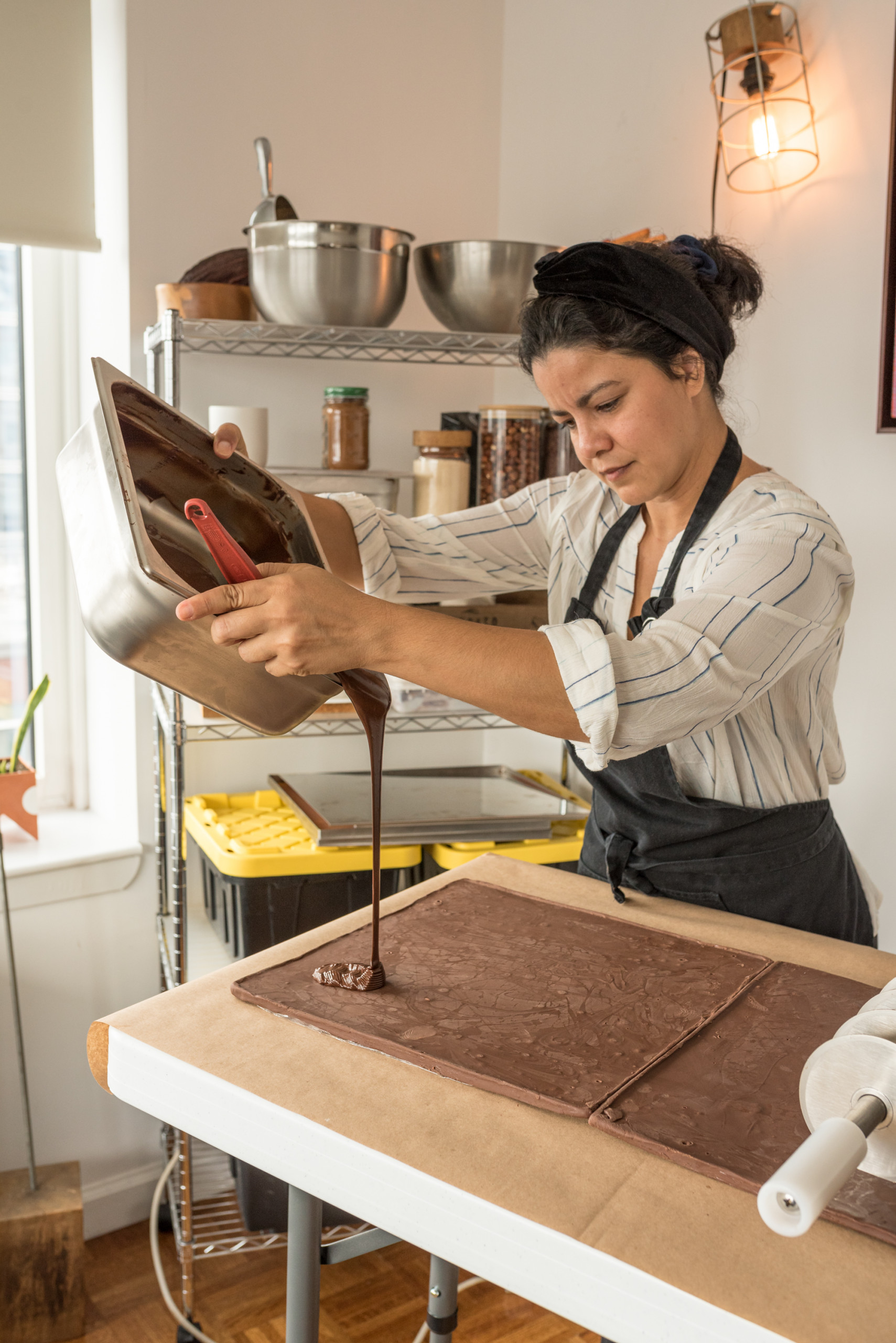 Person in apron pours liquid chocolate over a chocolate slab