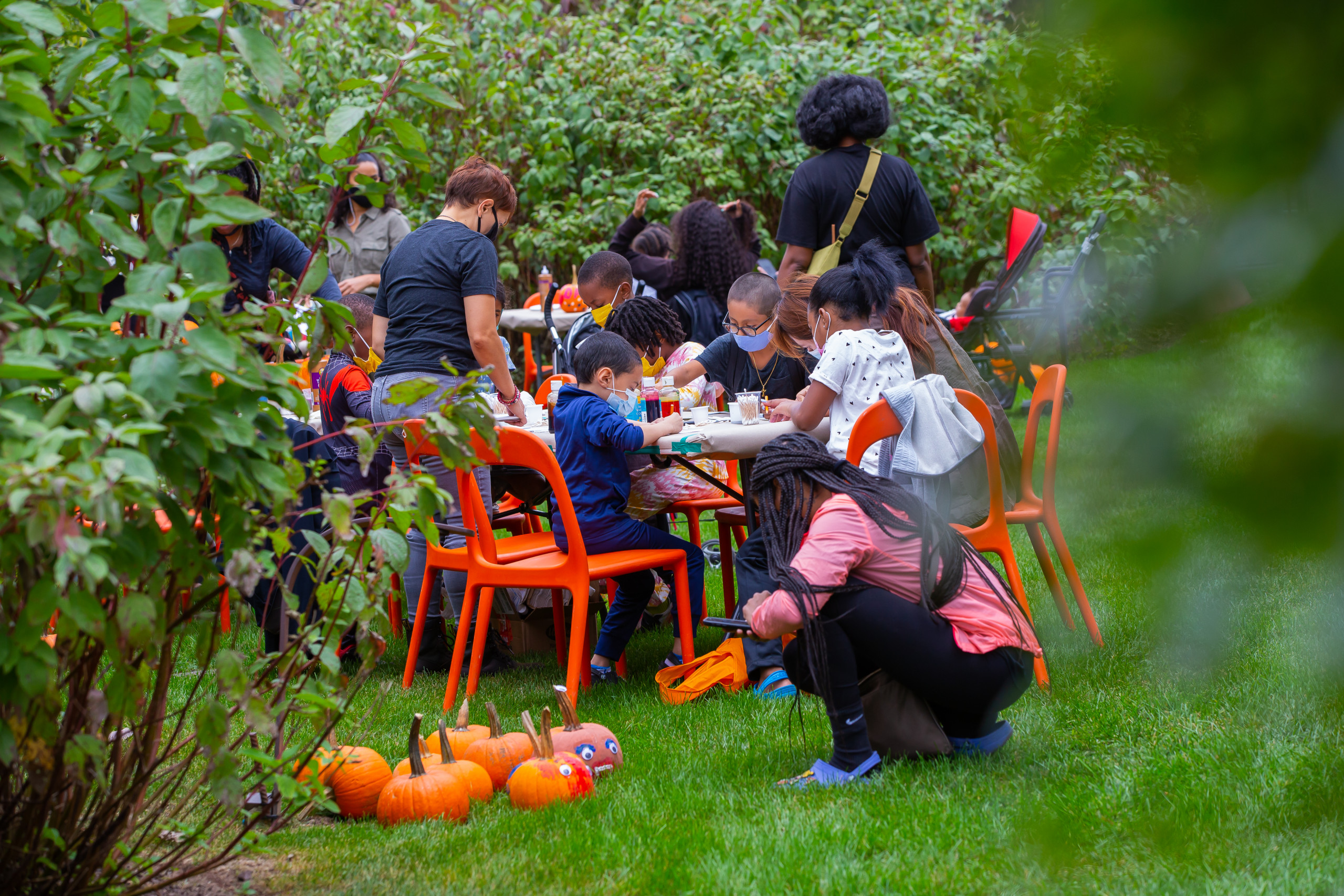 Children and adults do crafts at a table in a garden at Weeksville Heritage Center