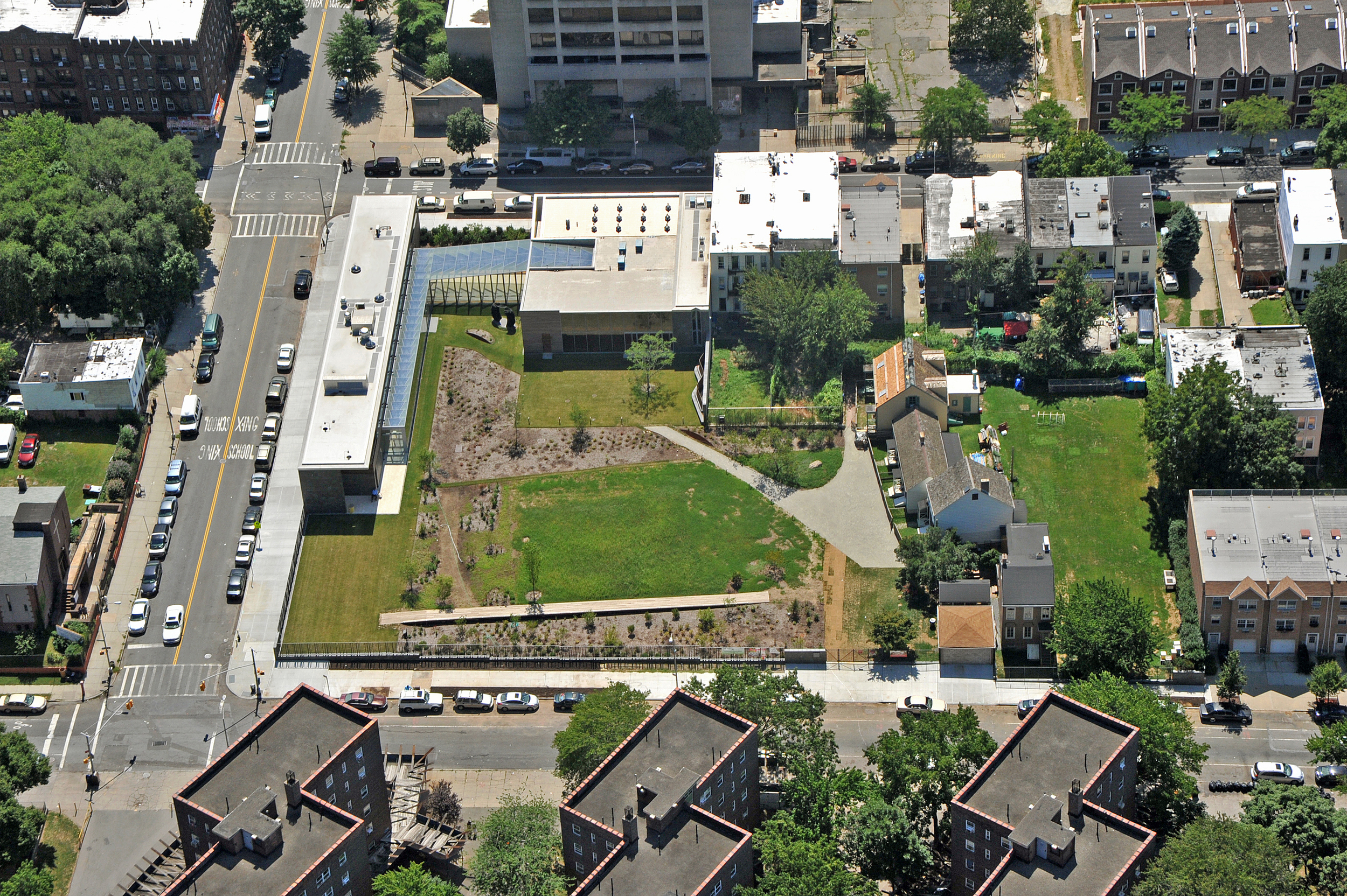 Aerial view of Weeksville Heritage Center site showing green space, diagonal paths delineating Hunterfly Road's footprint, and Hunterfly Road houses